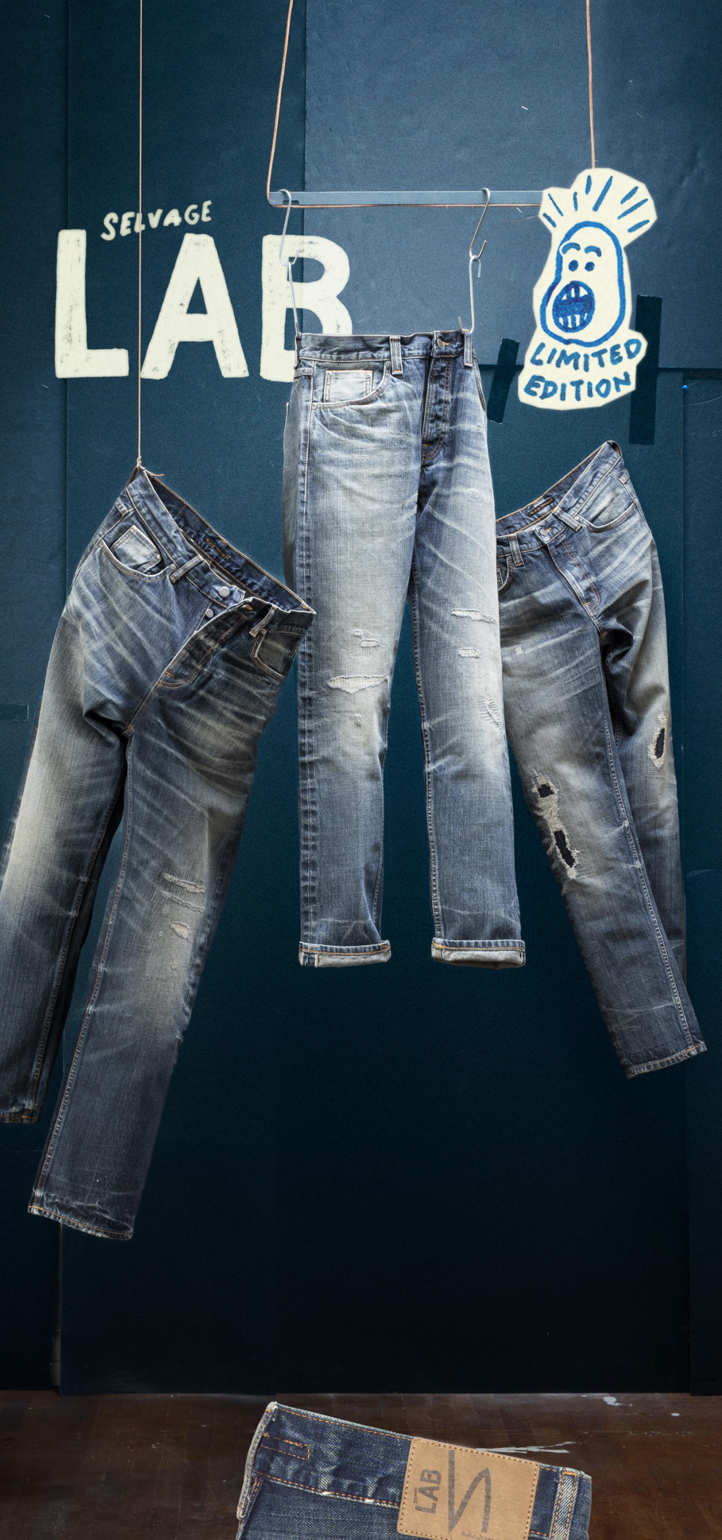 Three pairs of distressed jeans hang against a dark backdrop with "Selvage LAB" text and illustrated graphics saying Limited Edition
