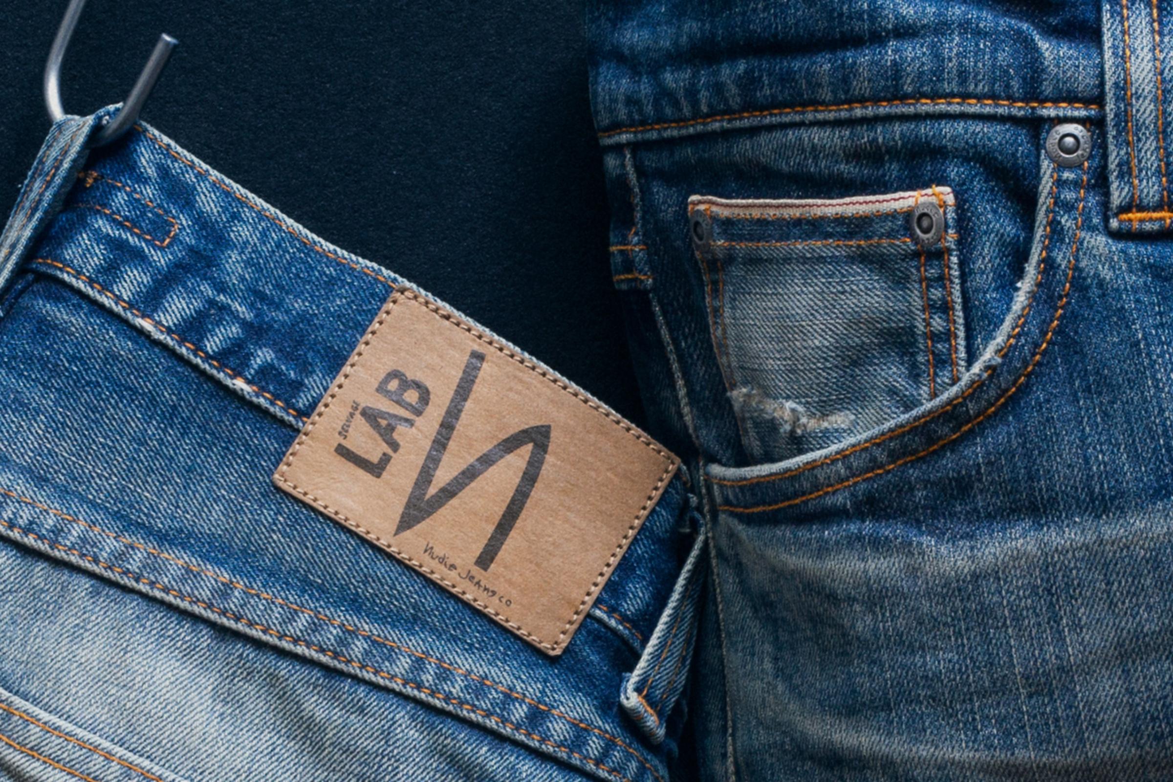Close-up of two pairs of blue jeans with visible stitching and a leather label reading "Selvage LAB"