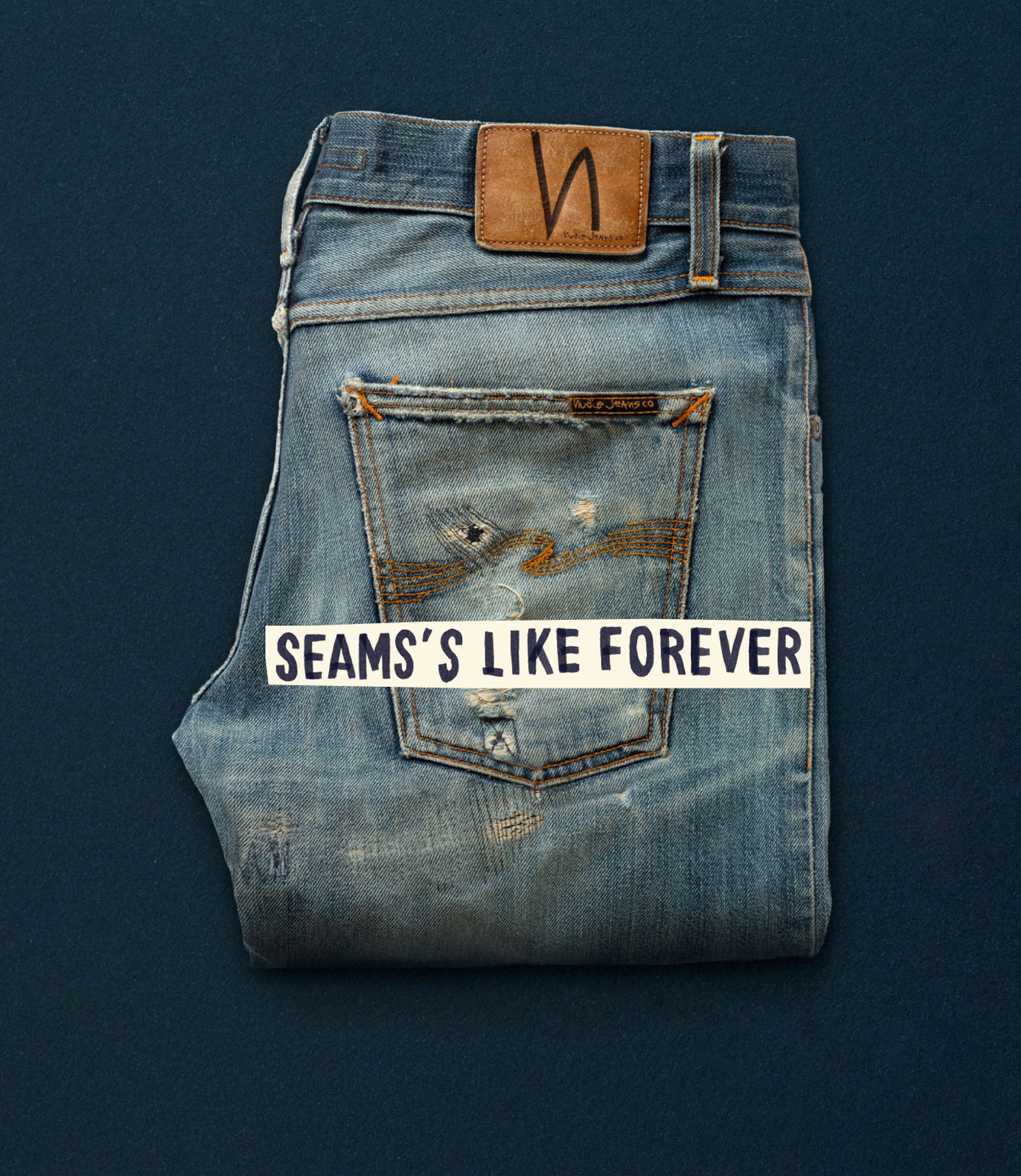 Folded distressed jeans with visible wear and a leather patch, placed on a dark surface. Text overlay reads, "SEAMS'S LIKE FOREVER."