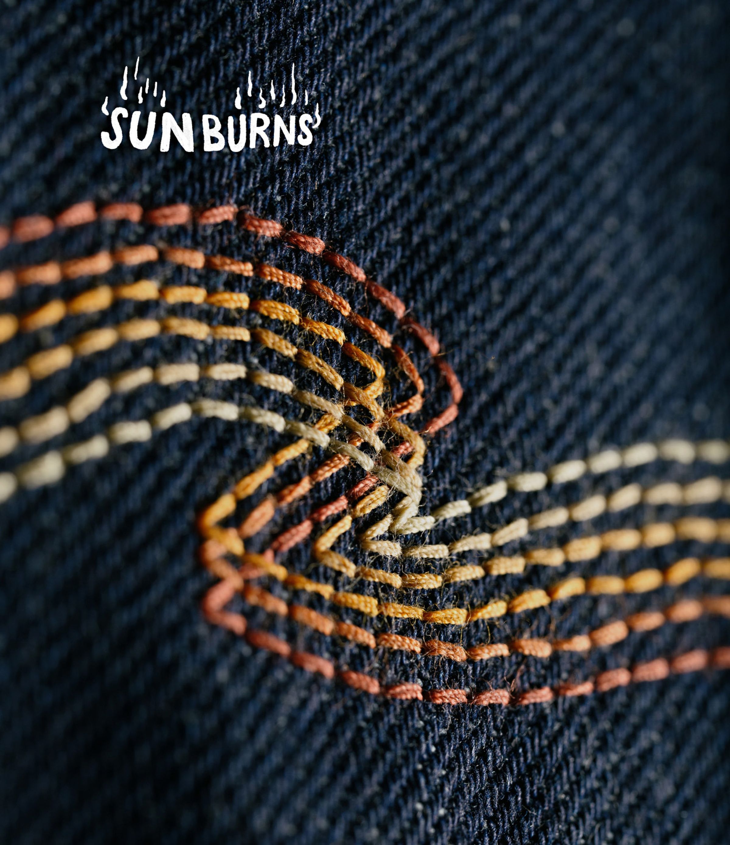 Close-up of colorful wave-like stitching on dark denim fabric, with the word "SUNBURNS" in white, stylized text in the top left corner.