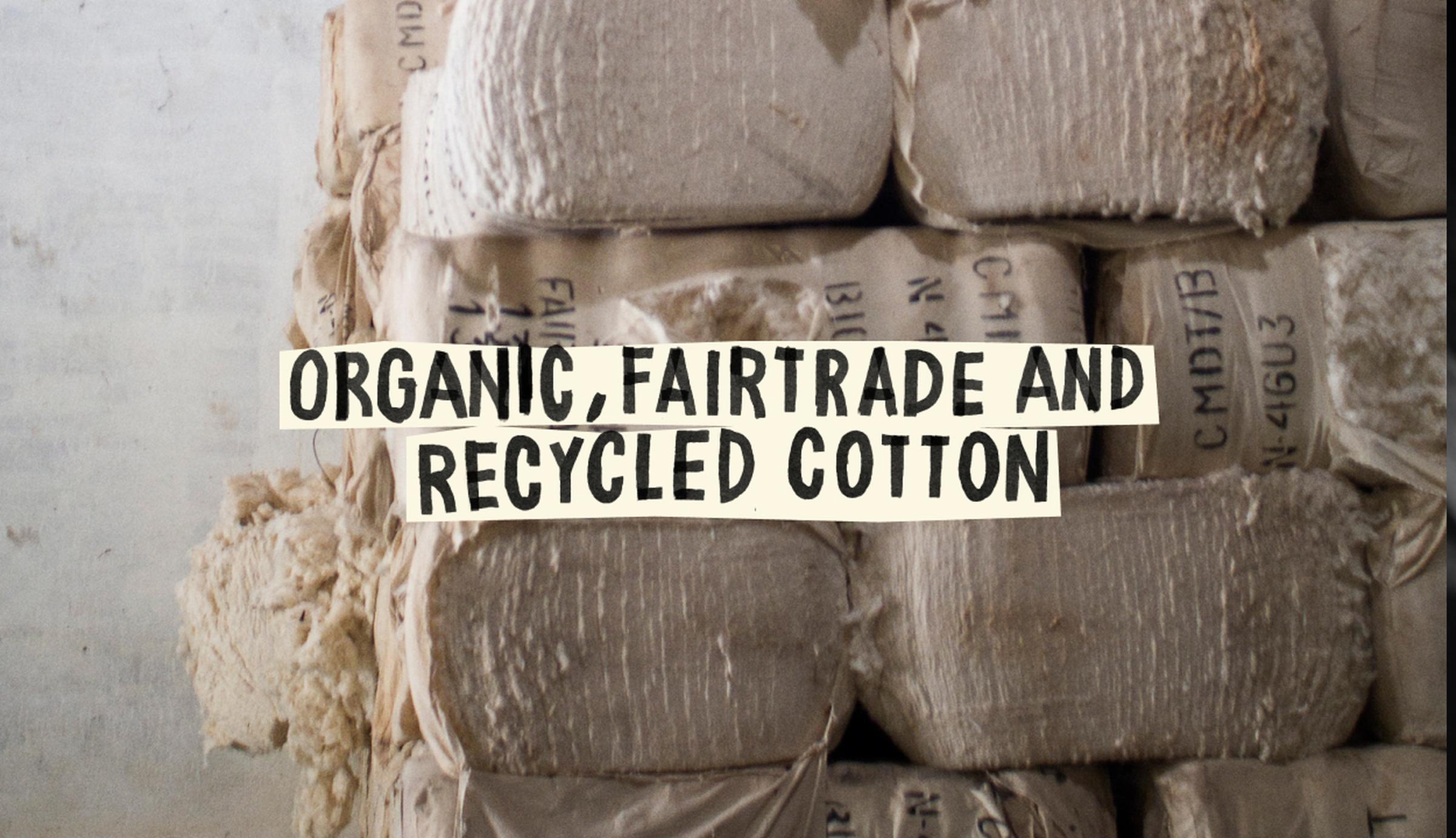 Bales of cotton labeled as organic, fairtrade, and recycled, stacked in a storage area.