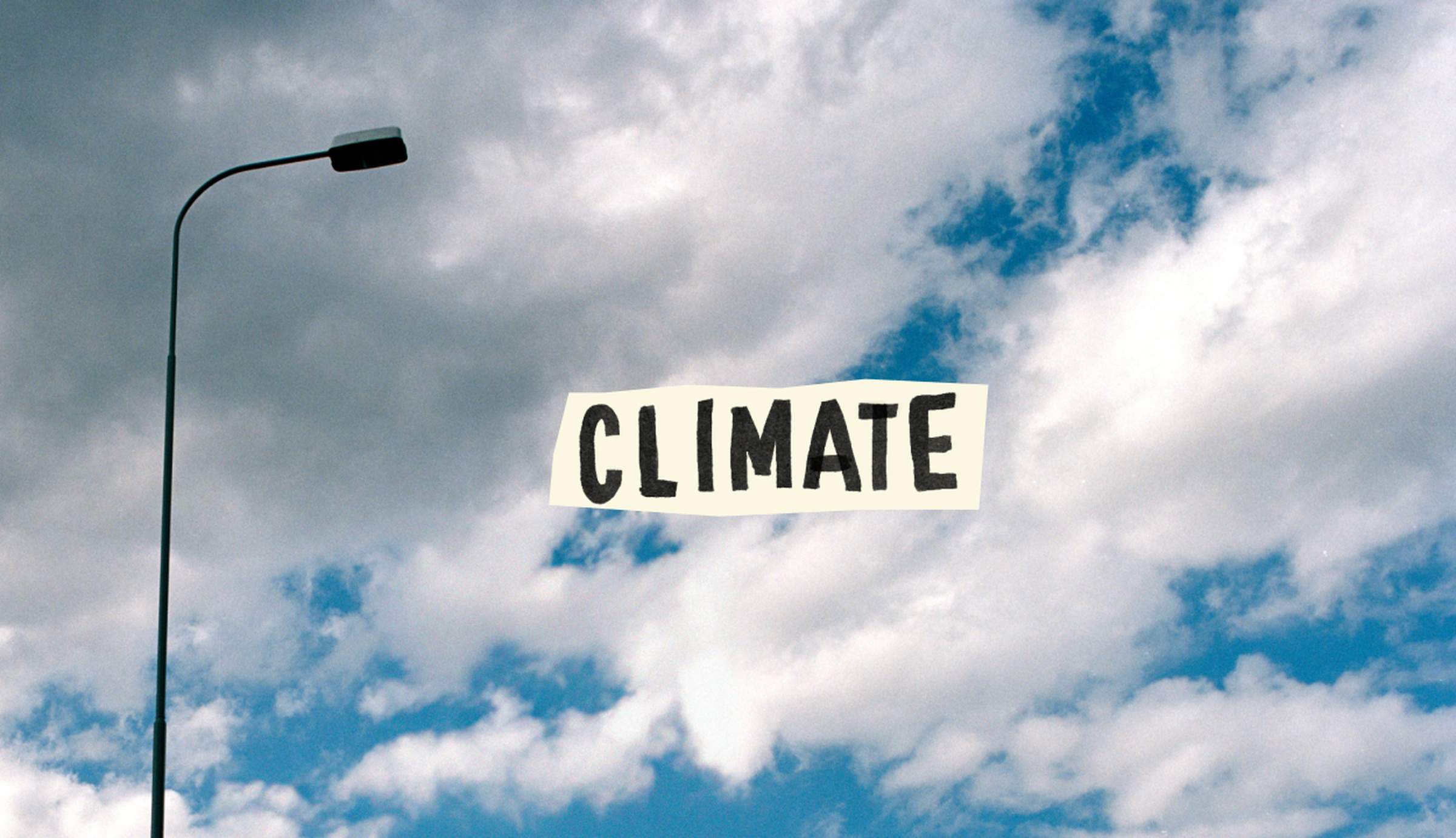 Streetlight against a cloudy blue sky with the word "CLIMATE" in bold letters across the center.