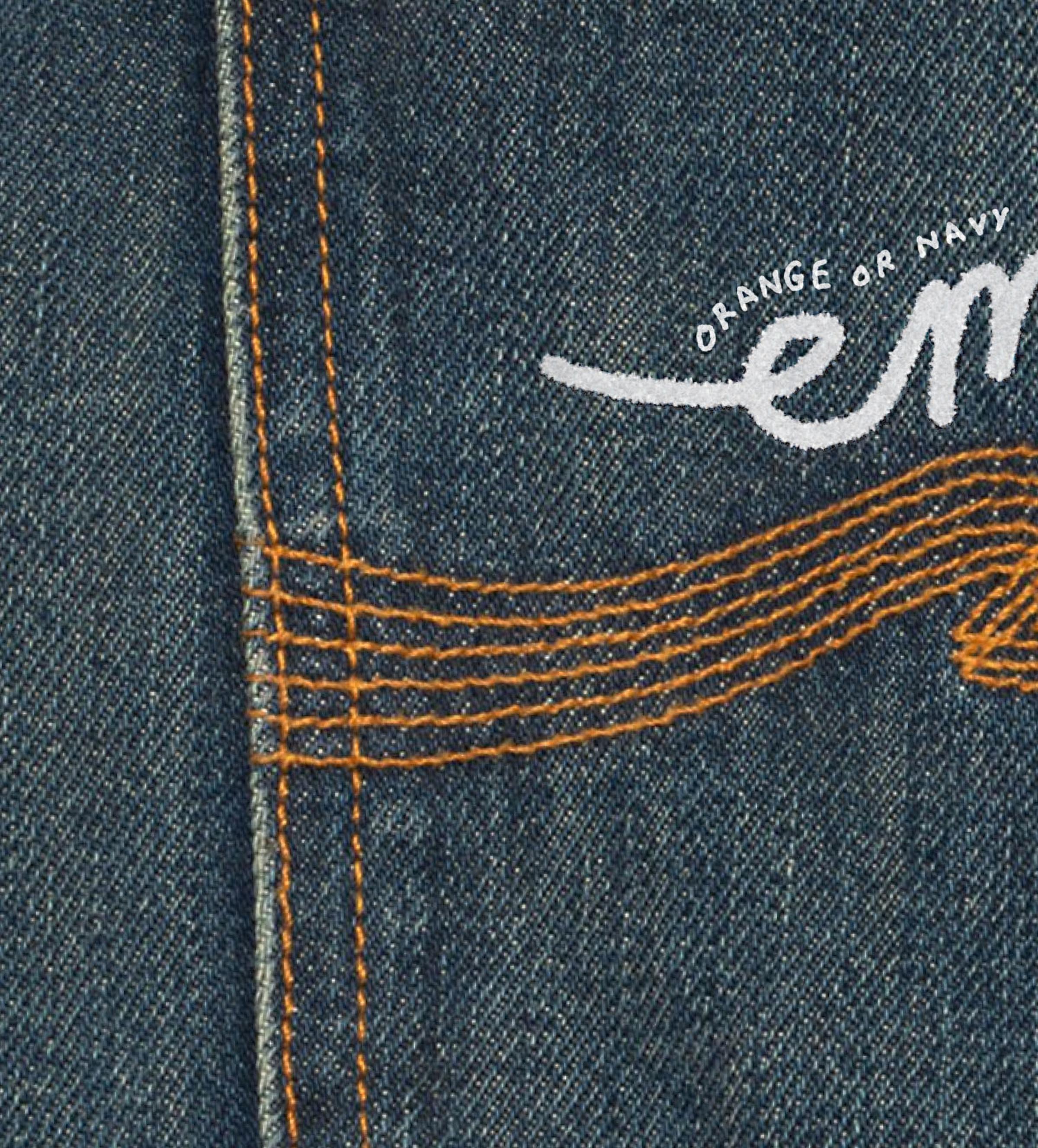 Close-up of blue denim with orange stitching and white cursive text partially visible.