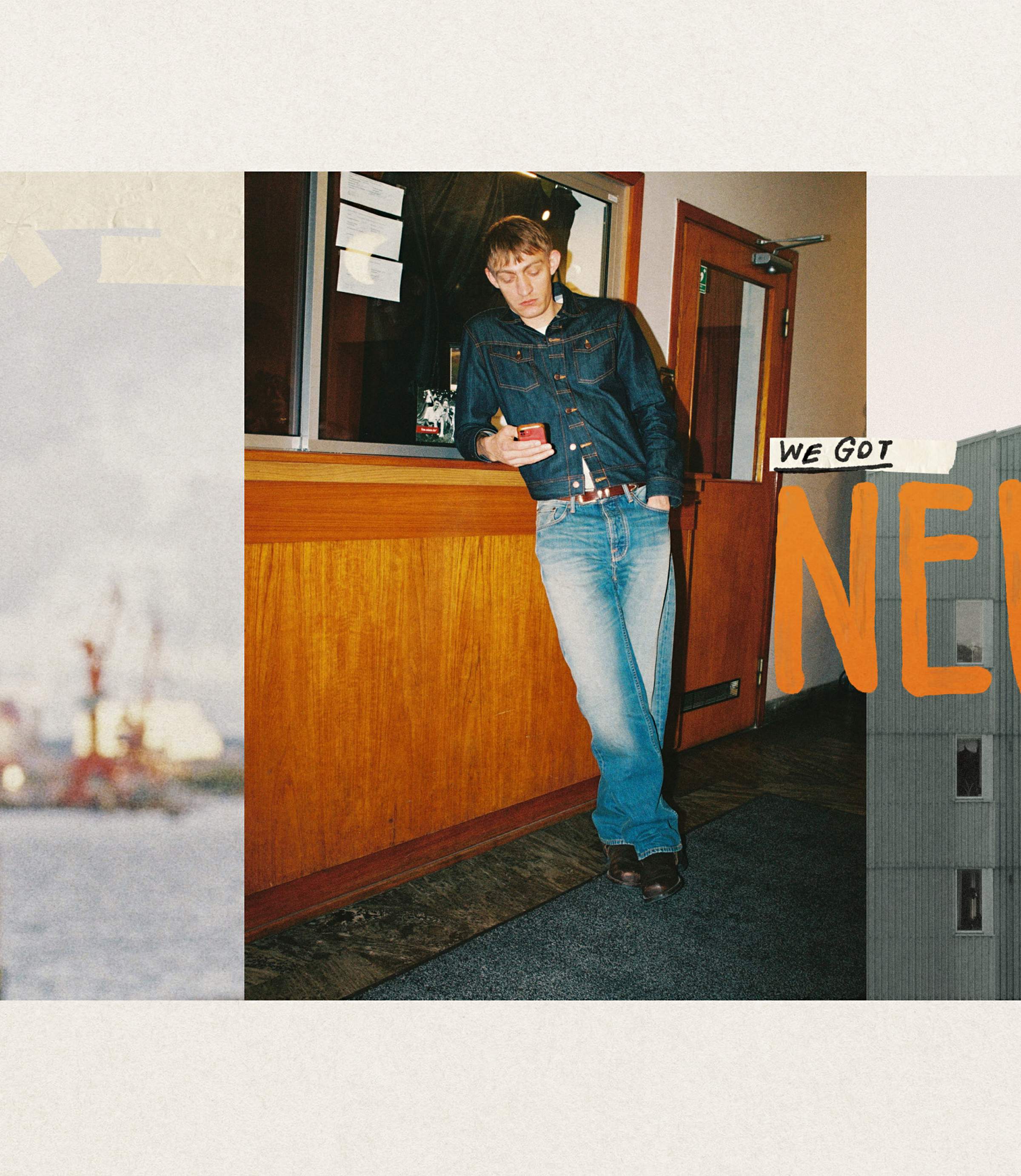 Person in denim outfit leaning against a counter, looking at a phone. Bold text "We Got" with partially visible letters "NEW" in the background.