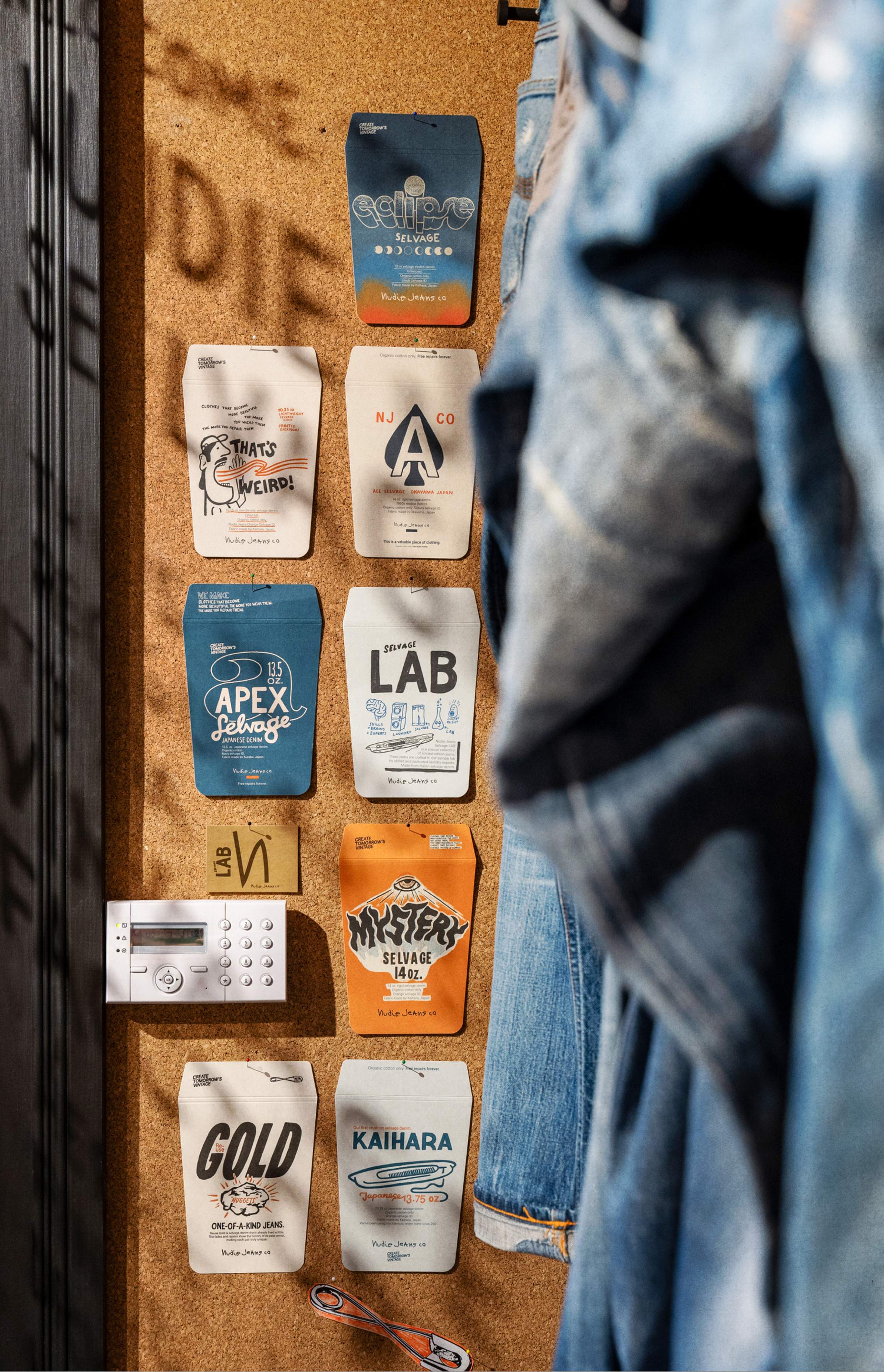 Corkboard displaying various colorful coffee bags, a security keypad, and hanging denim jackets.