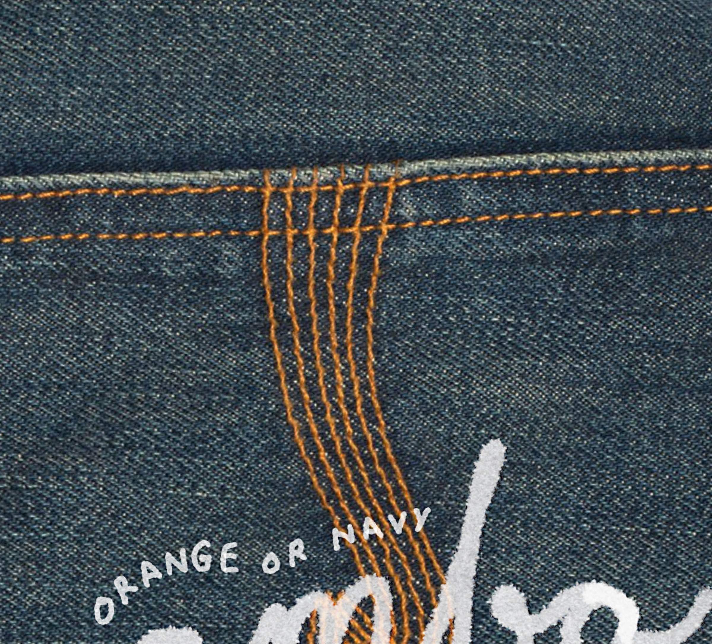 Close-up of denim fabric with orange stitching and white text that reads "ORANGE OR NAVY."