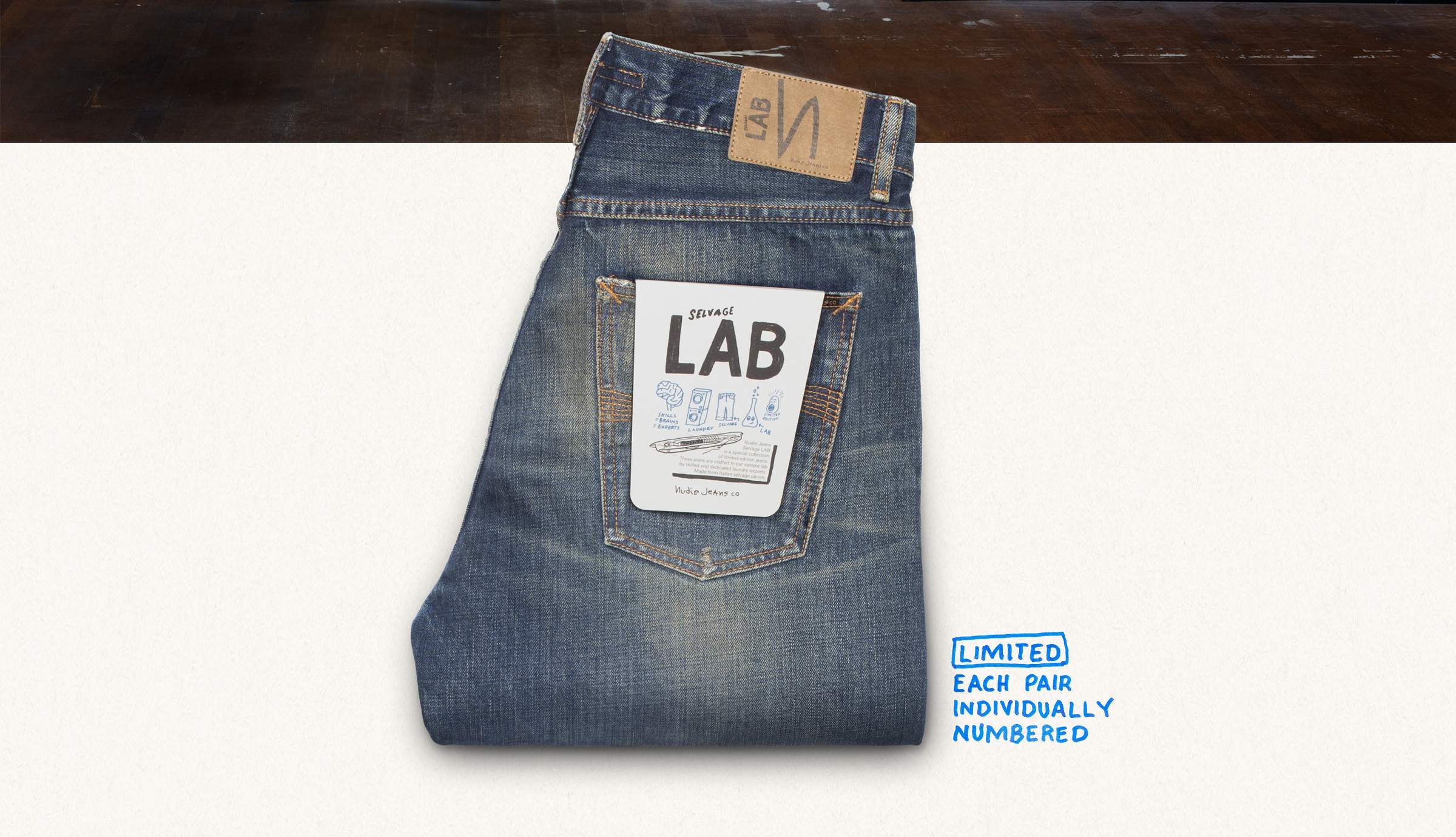 Folded blue jeans with a "Selvage LAB" label on the back pocket, laid on a white surface. A note reads "LIMITED EACH PAIR INDIVIDUALLY NUMBERED."