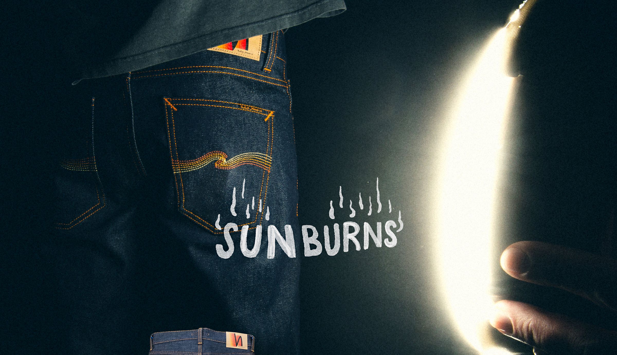 Close-up of a person in jeans with "Sunburns" text and a bright light source on the right, creating a dramatic contrast.