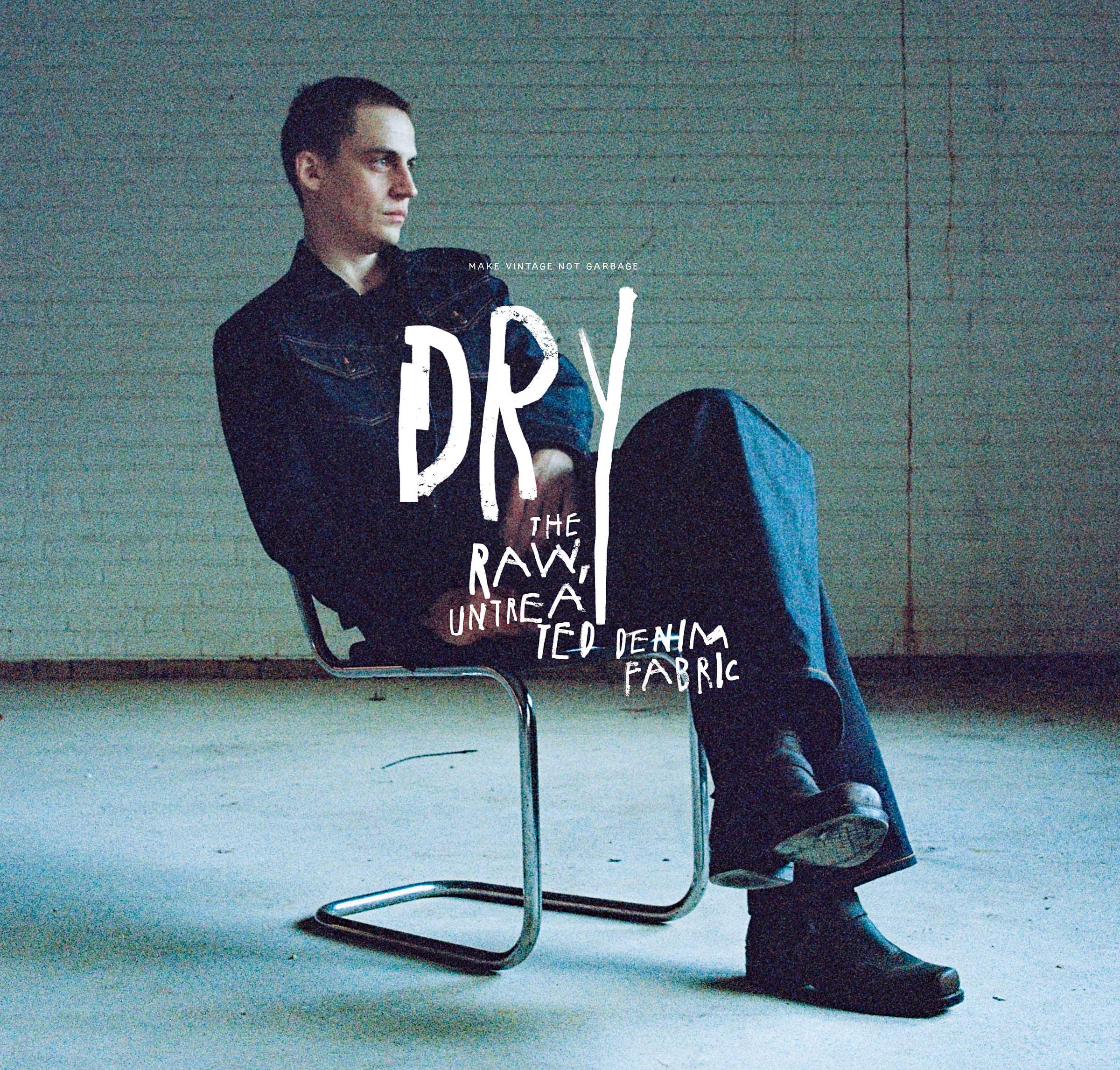 Person seated on a metal chair in a dimly lit room, wearing dark clothing. Text overlay reads "DRY: The Raw, Untreated Denim Fabric."