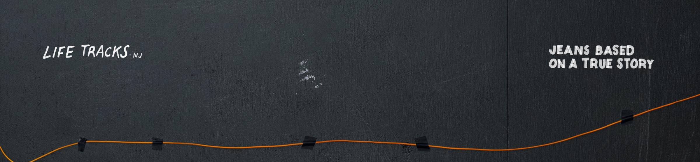 Black wall with an orange line across, labeled "Life Tracks NJ" and "Jeans Based on a True Story."