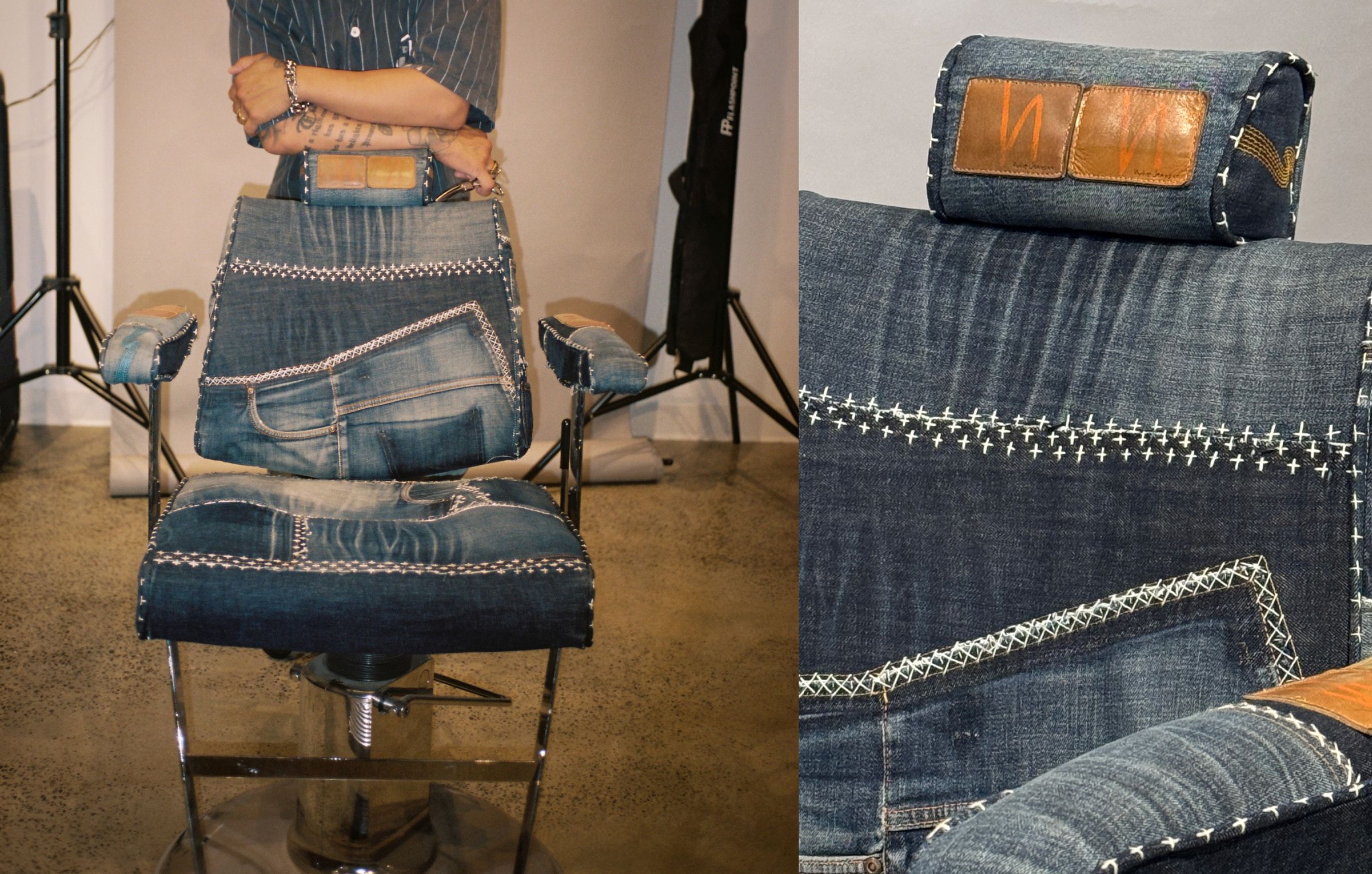 A barber chair upholstered with denim fabric, featuring stitched details and leather accents.
