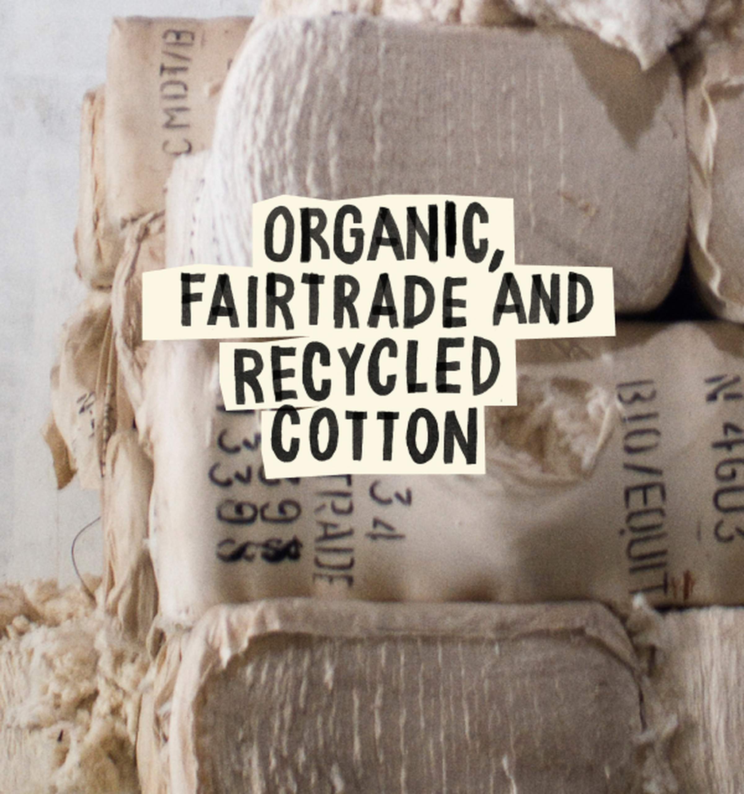 Bales of cotton labeled as organic, fairtrade, and recycled, stacked in a storage area.