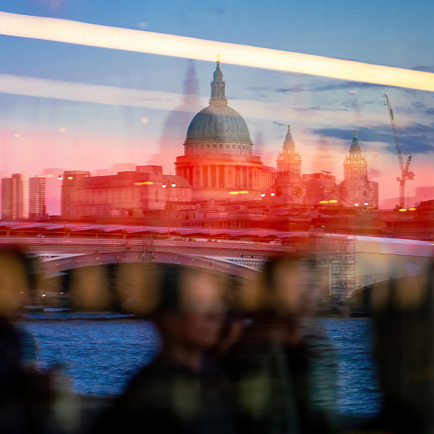 Reflections of St. Paul's Cathedral and a cityscape at sunset, merging with blurred silhouettes of people and interior lights.