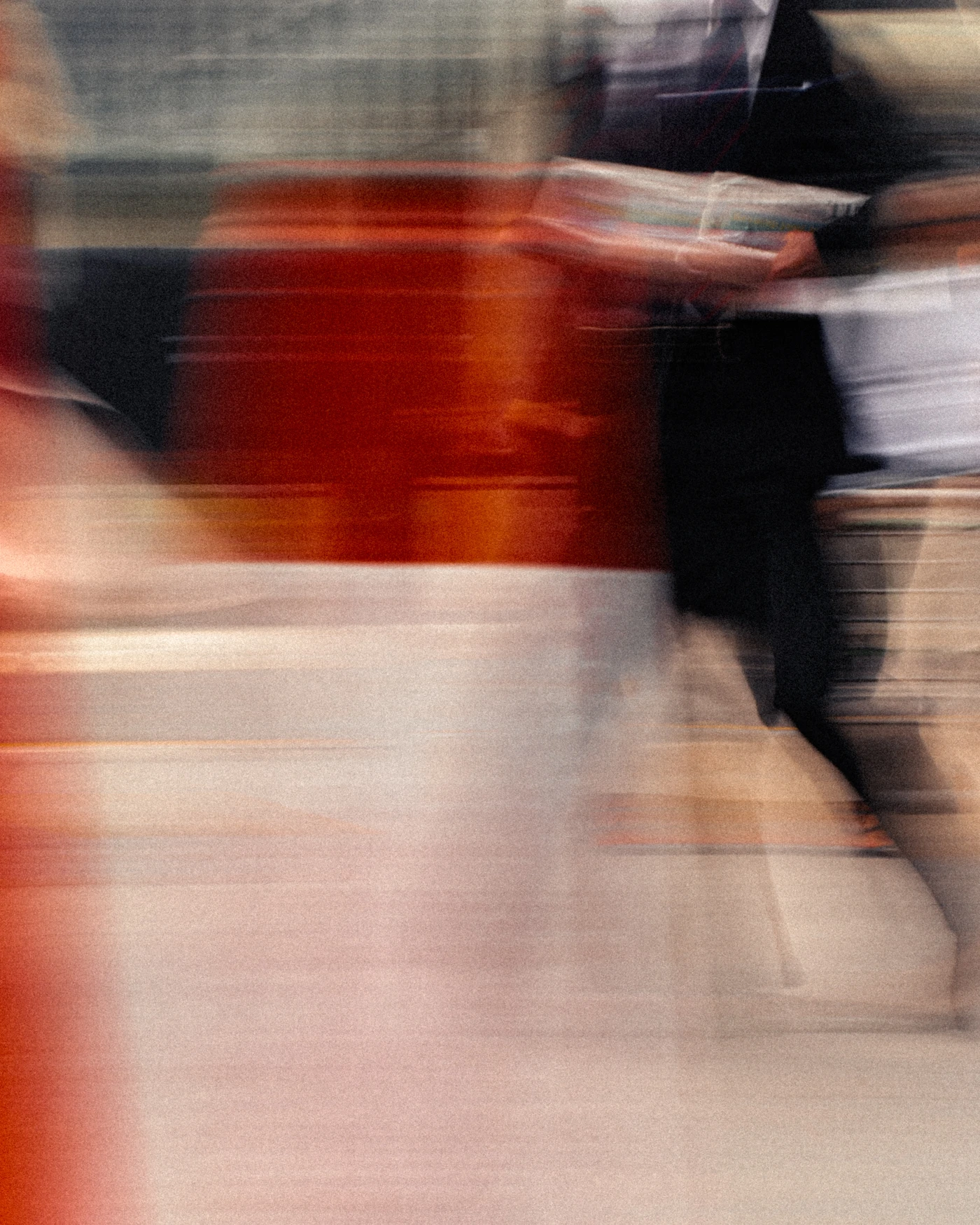 Abstract blurred image of a person holding a newspaper, with streaks of red and white creating a sense of motion and energy.