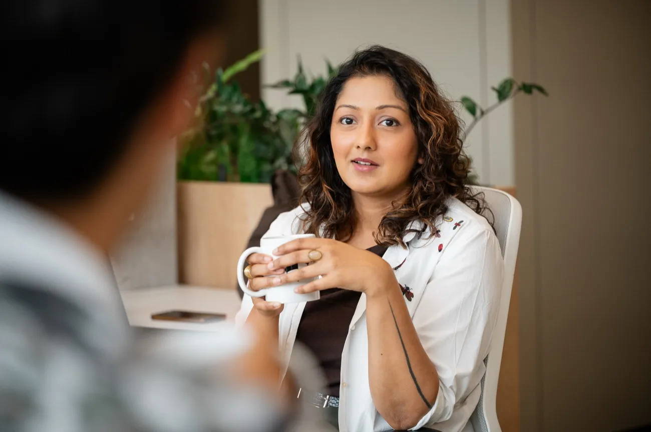 Woman holding a mug, talking with a colleague in the office
