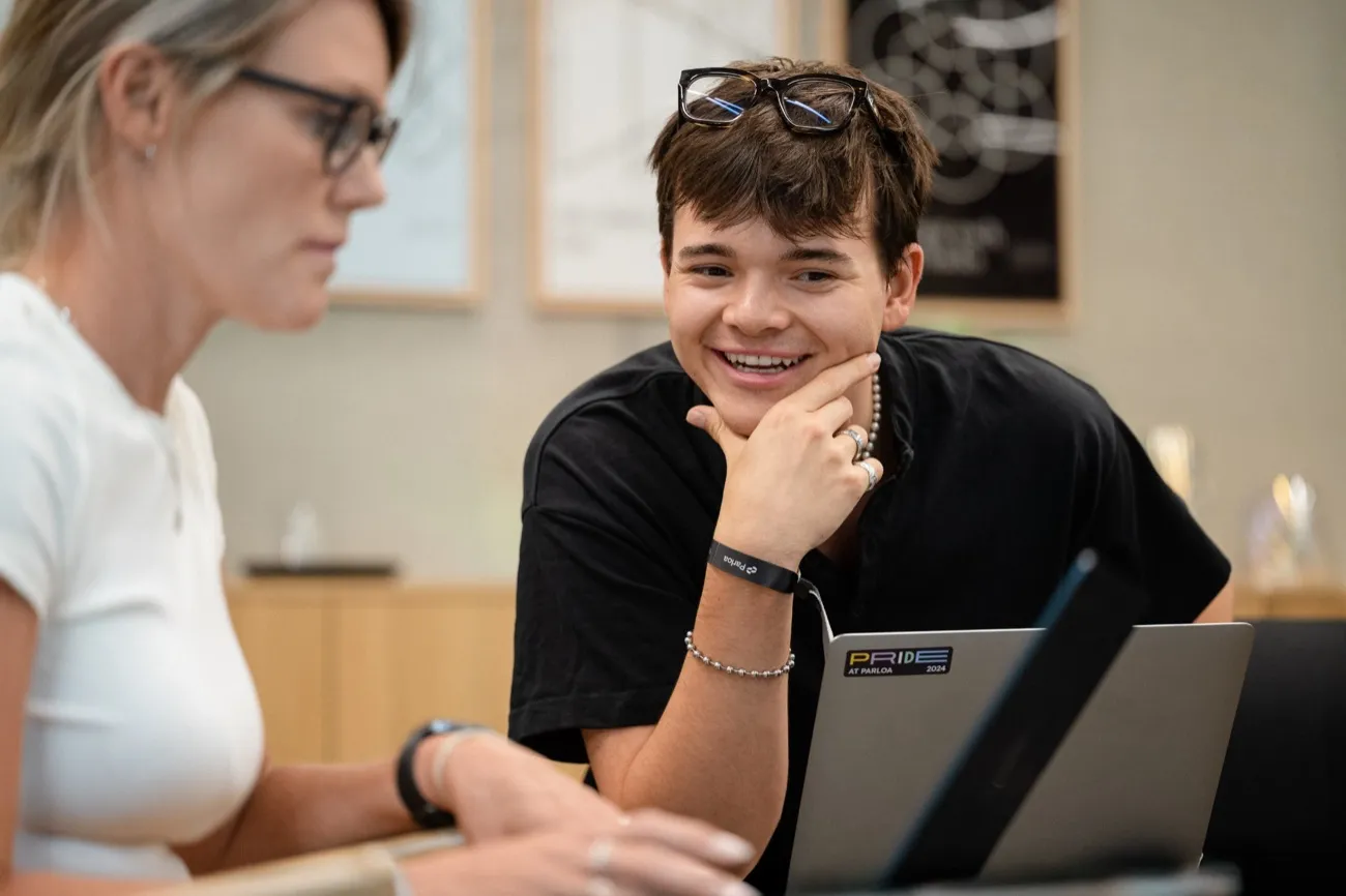 Two colleagues smiling while working on a laptop