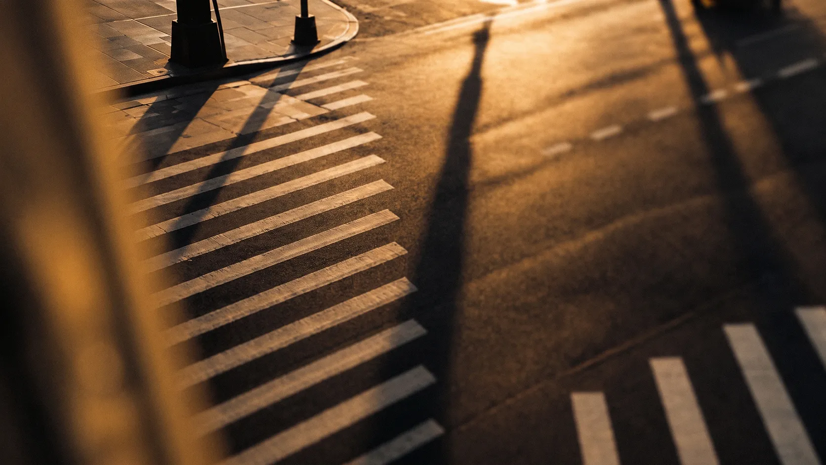 Zebrastreifen und lange Schatten auf einer Straße zur goldenen Stunde