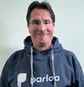 Smiling person wearing glasses and a blue hoodie with the logo "parloa" on it, set against a plain background.