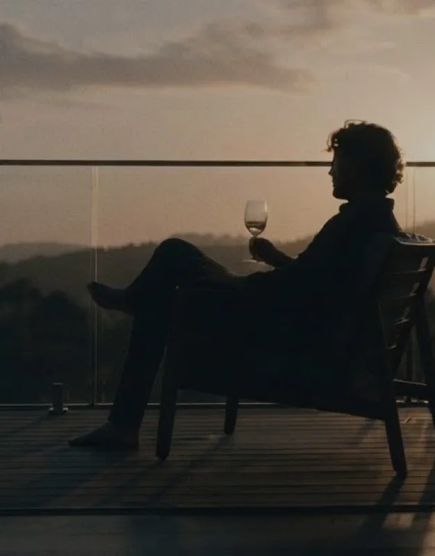 Man sitting on a balcony at sunset