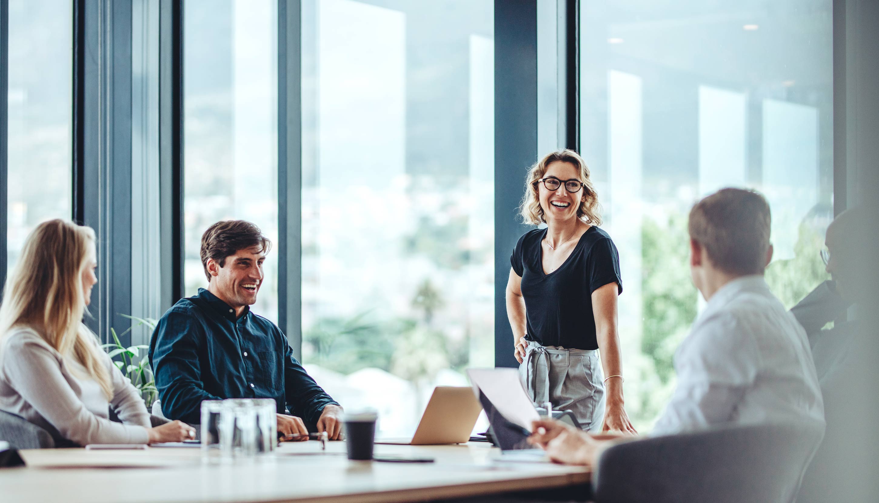 A group of professionals are laughing during a meeting in an office.