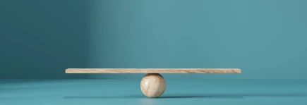 Wooden plank balanced on a round wooden sphere against a teal background.