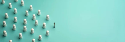 A lone figure faces a group of white game pieces arranged in formation on a teal background, symbolizing leadership or confrontation.