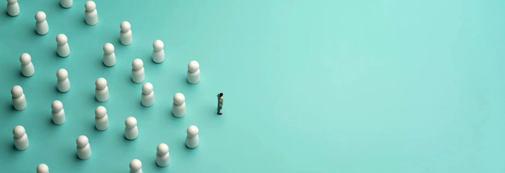 A lone figure faces a group of white game pieces arranged in formation on a teal background, symbolizing leadership or confrontation.