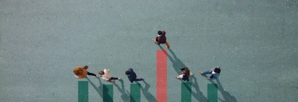 Group of young adults, photographed from above, on various painted tarmac surface, at sunrise.