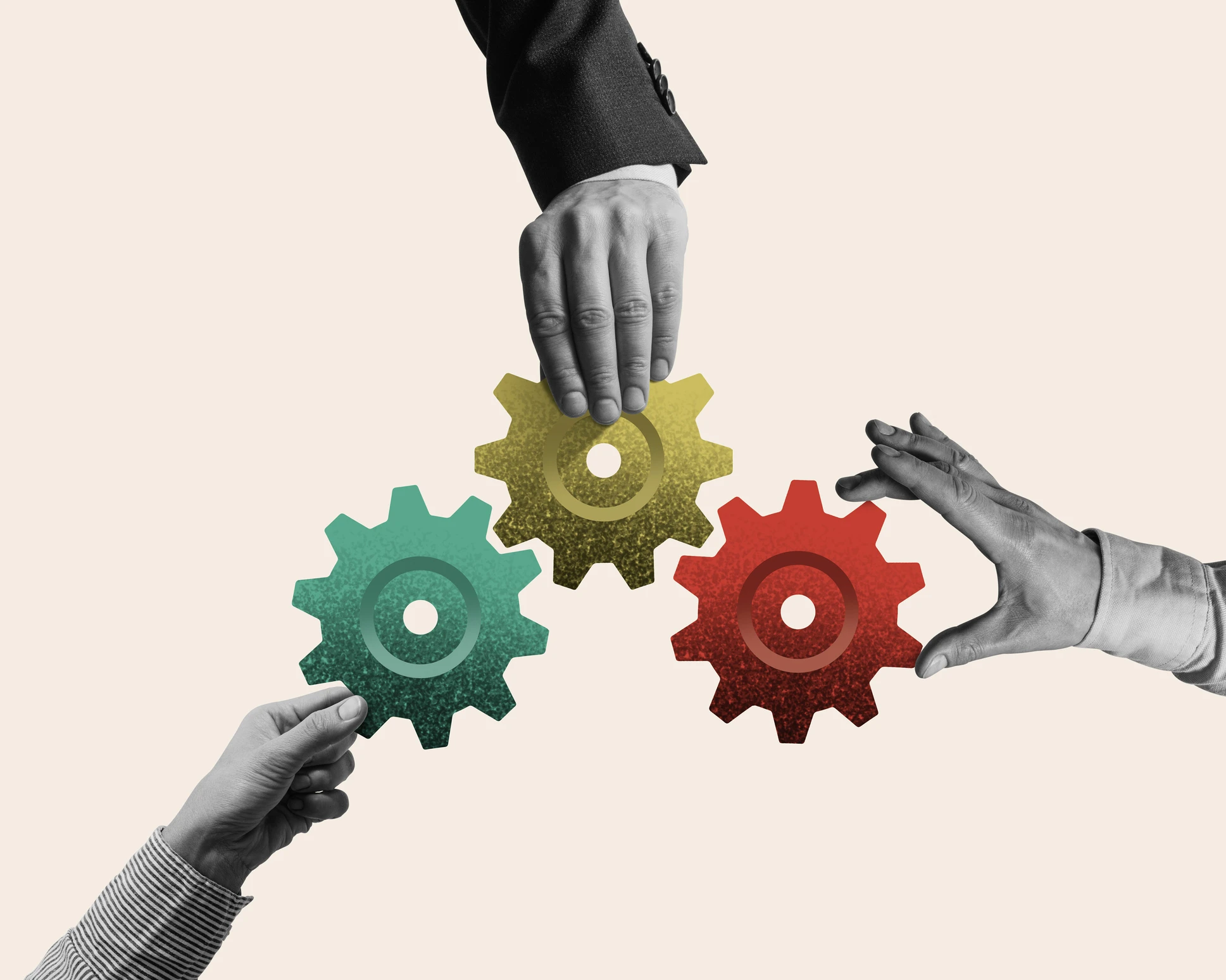 Three hands hold interlocking green, yellow, and red gears, symbolizing teamwork and collaboration against a plain background.