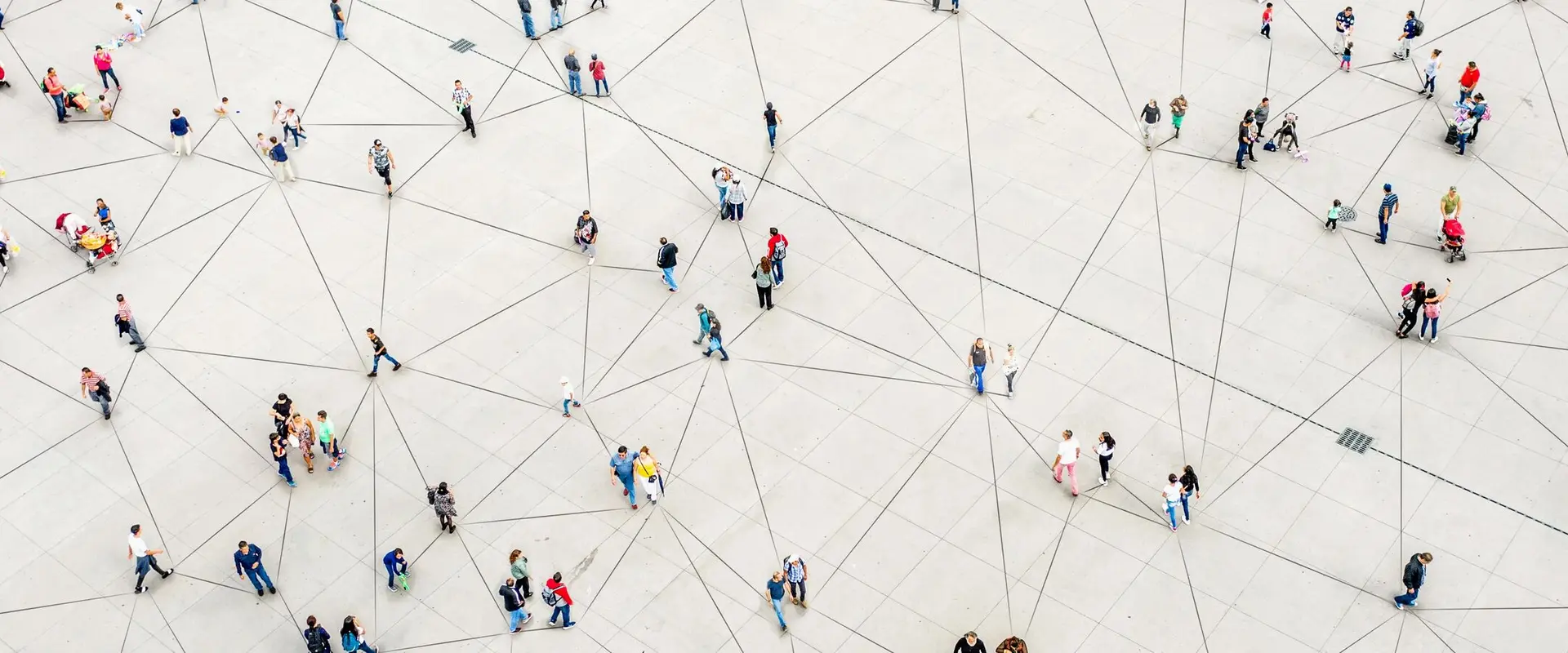 Aerial view of a large open plaza where groups of people walk and gather, connected by thin dark lines on the ground that form a web like pattern suggesting a network of human connections.
