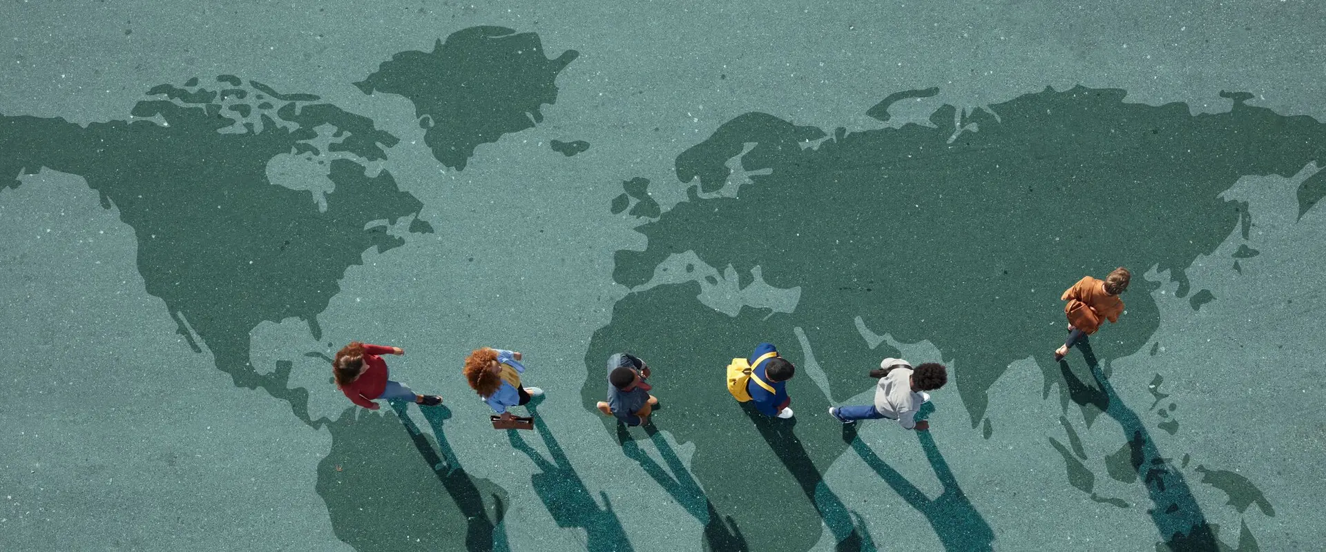 People walking on a world map painted on the ground, casting long shadows across different continents.