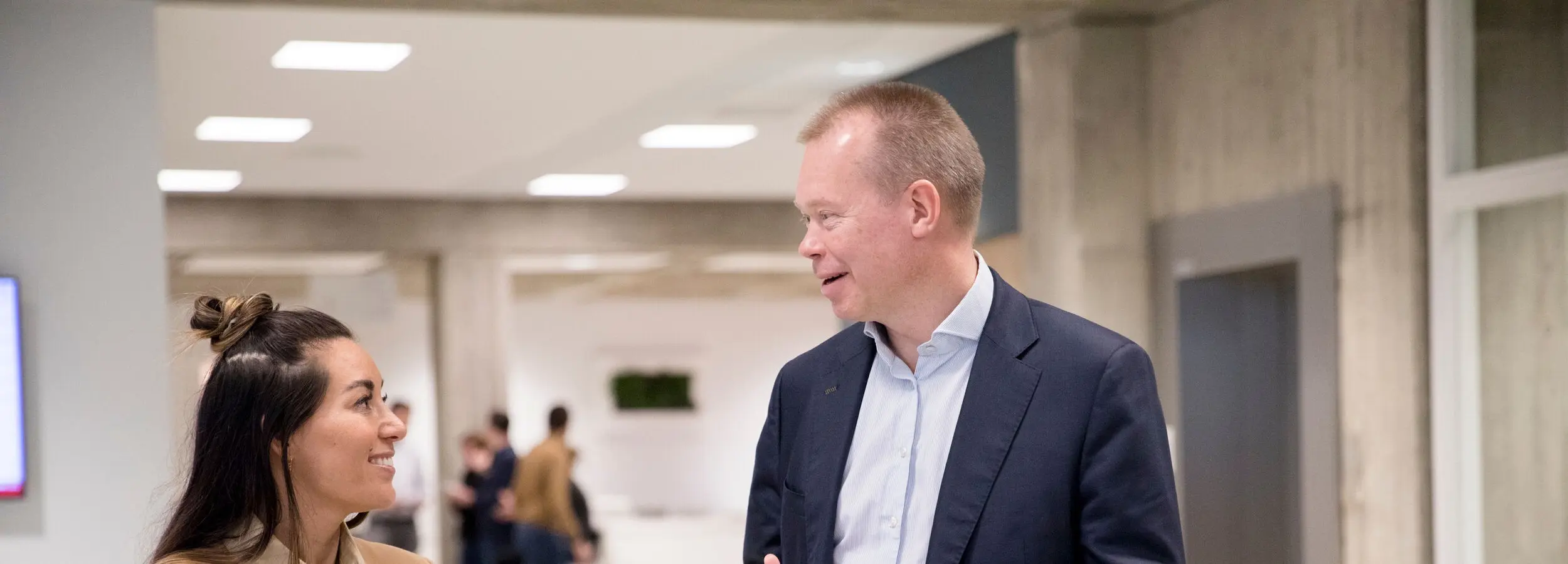 A man and woman engaged in conversation in a modern office setting.