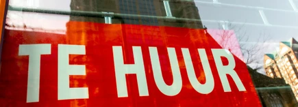Red "Te Huur" sign in a window, indicating a space available for rent, with reflections of buildings in the glass.