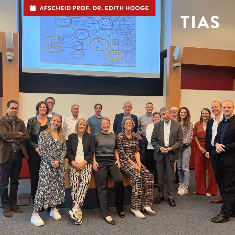 A group of people posing together in a classroom setting with a presentation screen behind them.