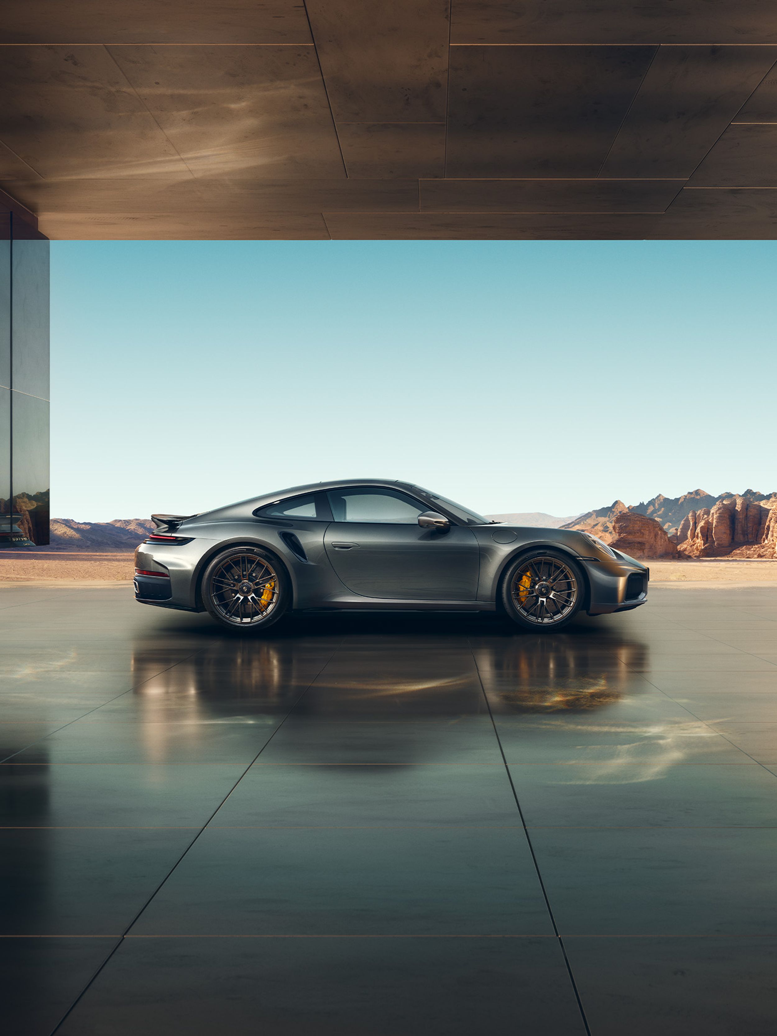 A silver 911 standing in a garage, with the outbacks behind.