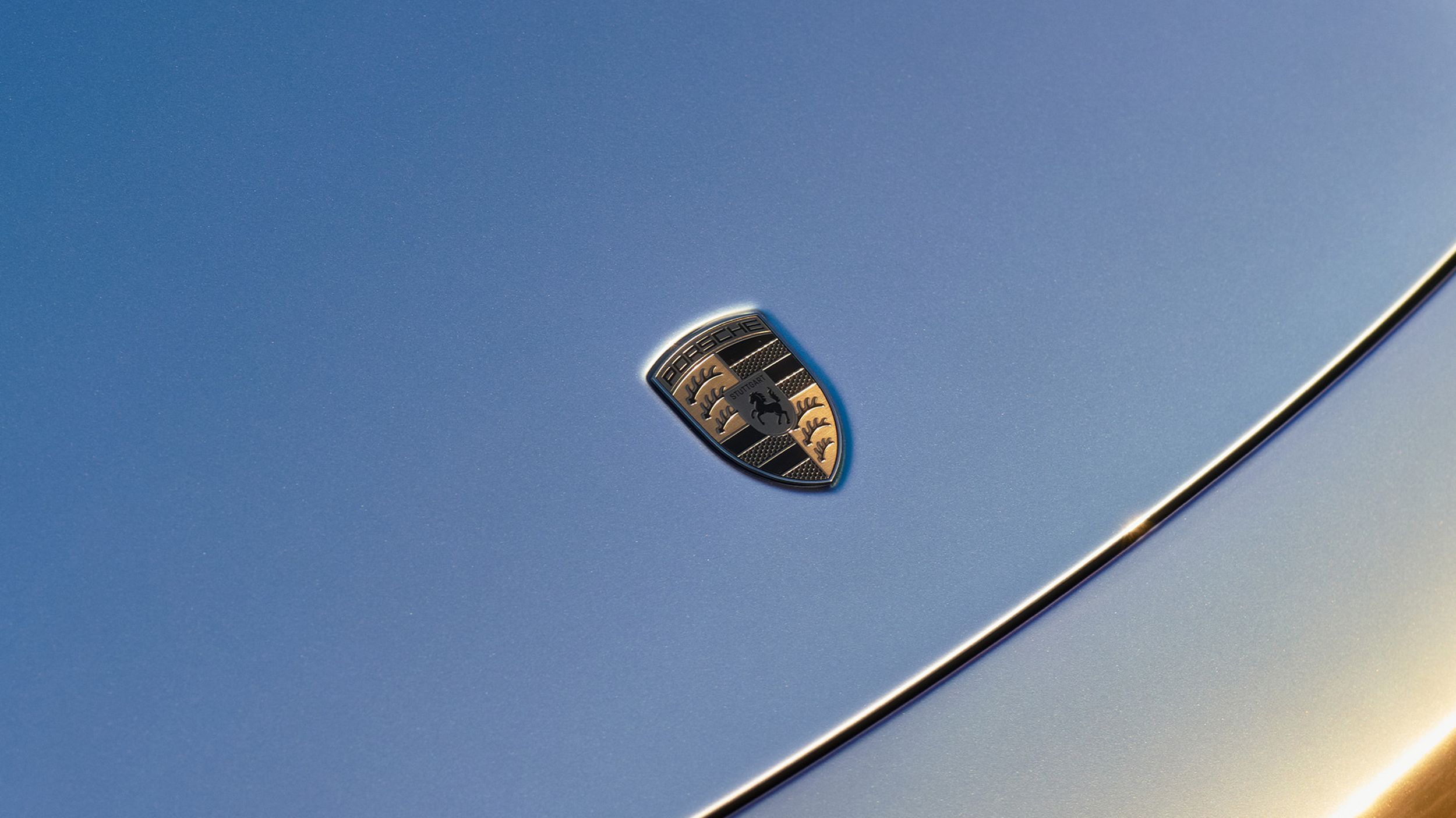 Close-up of the Porsche crest on a car hood.