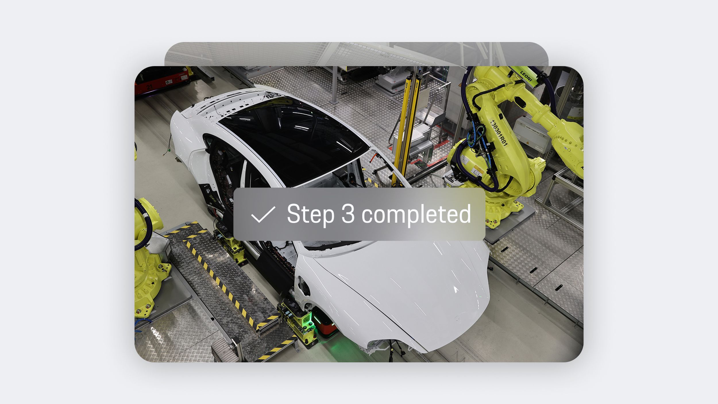 App view showing white Porsche body on assembly line with yellow robotic arms and overlay text ‘Step 3 completed’.
