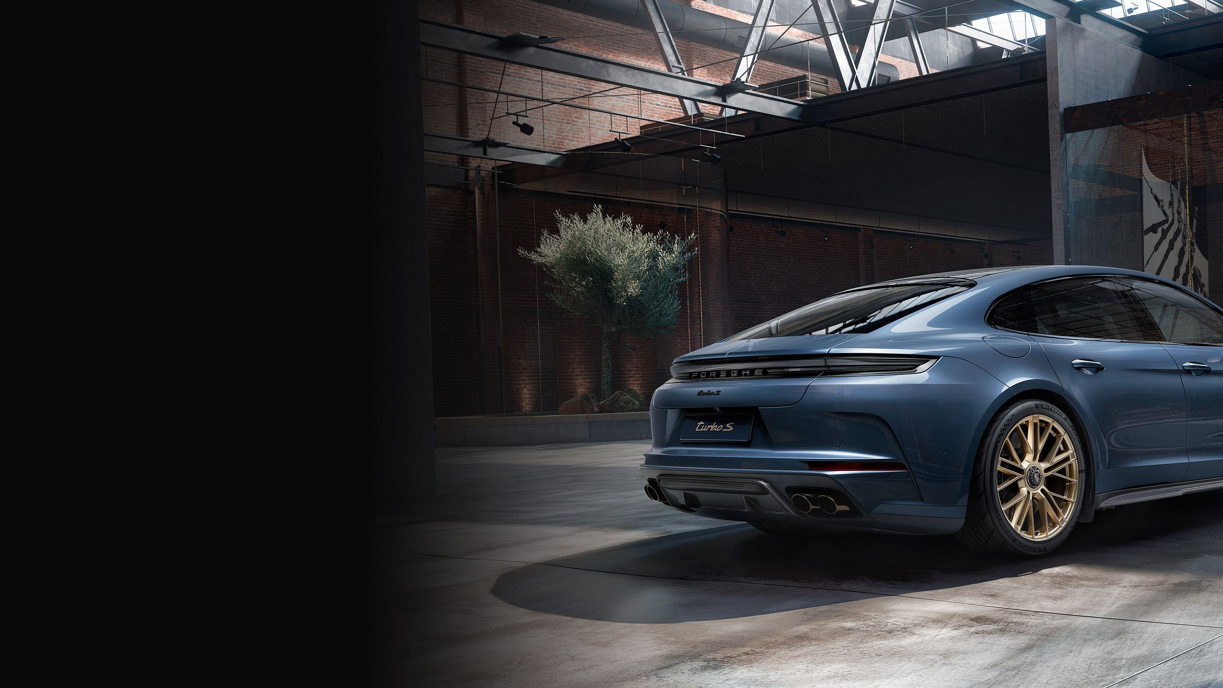 Porsche Exclusive Manufaktur Panamera Turbo S E-Hybrid in Yachting Blue Metallic in a warehouse. View of side and rear end.