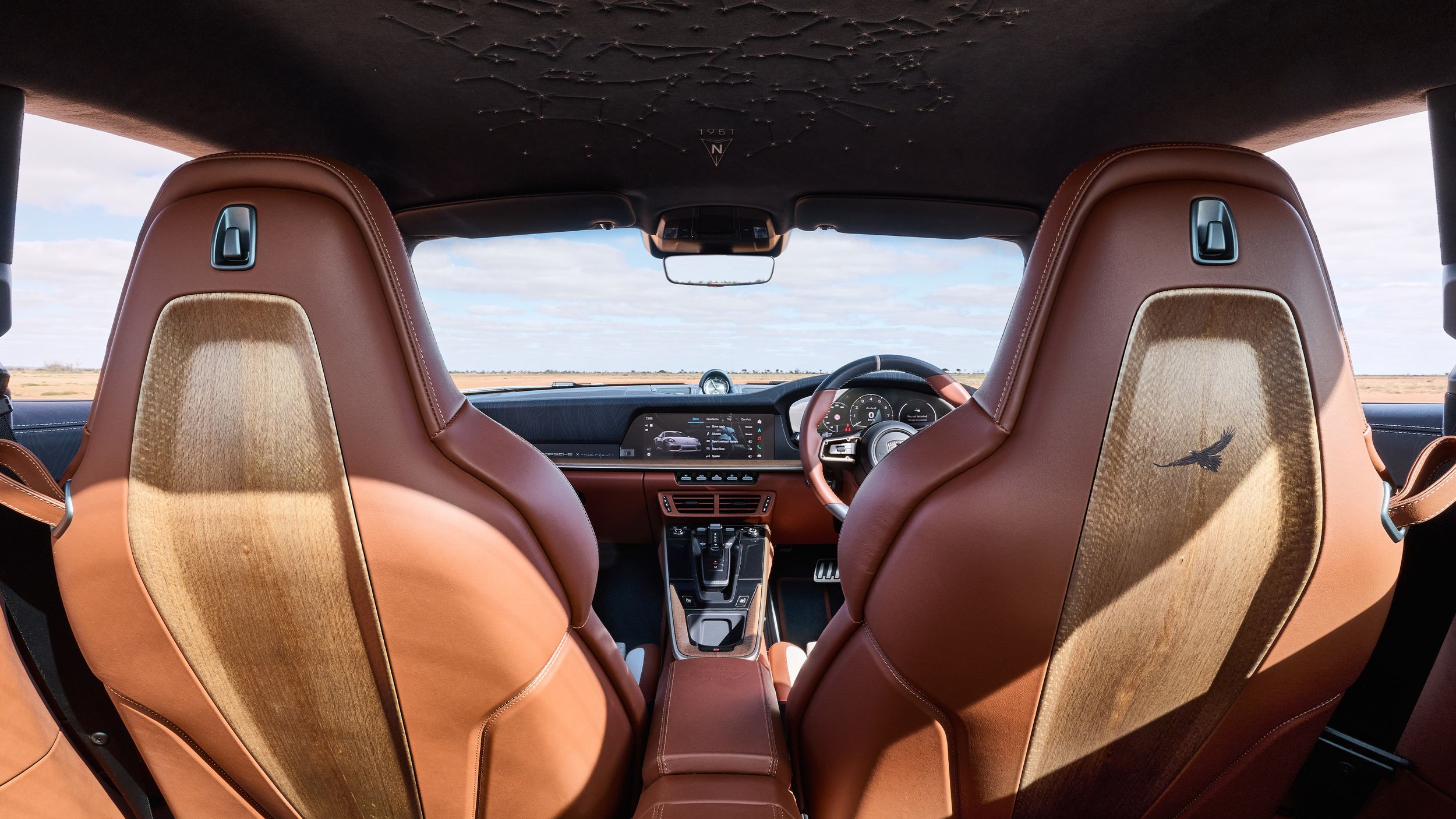 View of the back of the seats, roof, and the cockpit of the 911 Turbo S Land Down Under, showcasing the embroidered map and the leather and timber used.