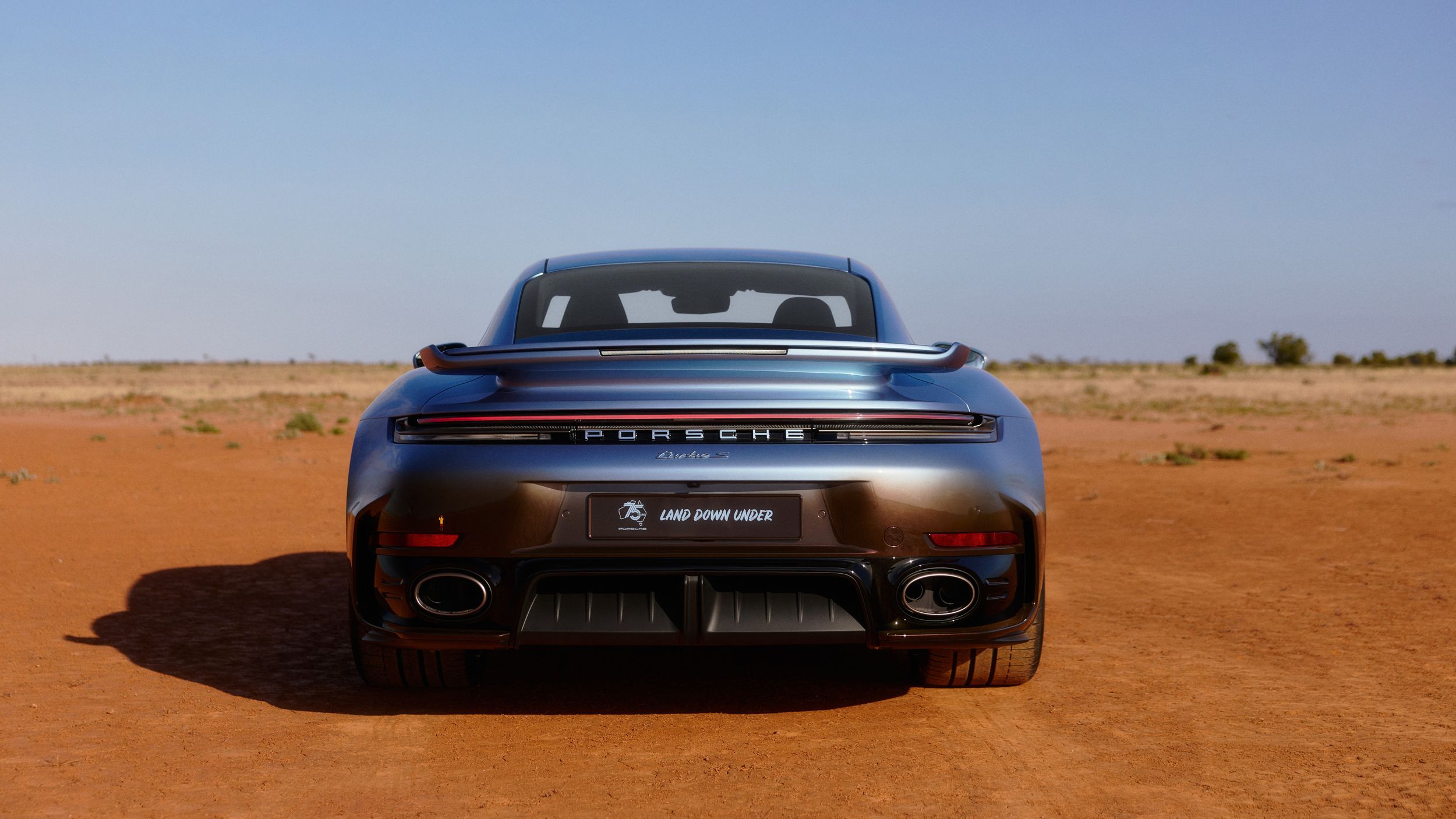Back shot of the 911 Turbo S Land Down Under driving on a road in the outback.