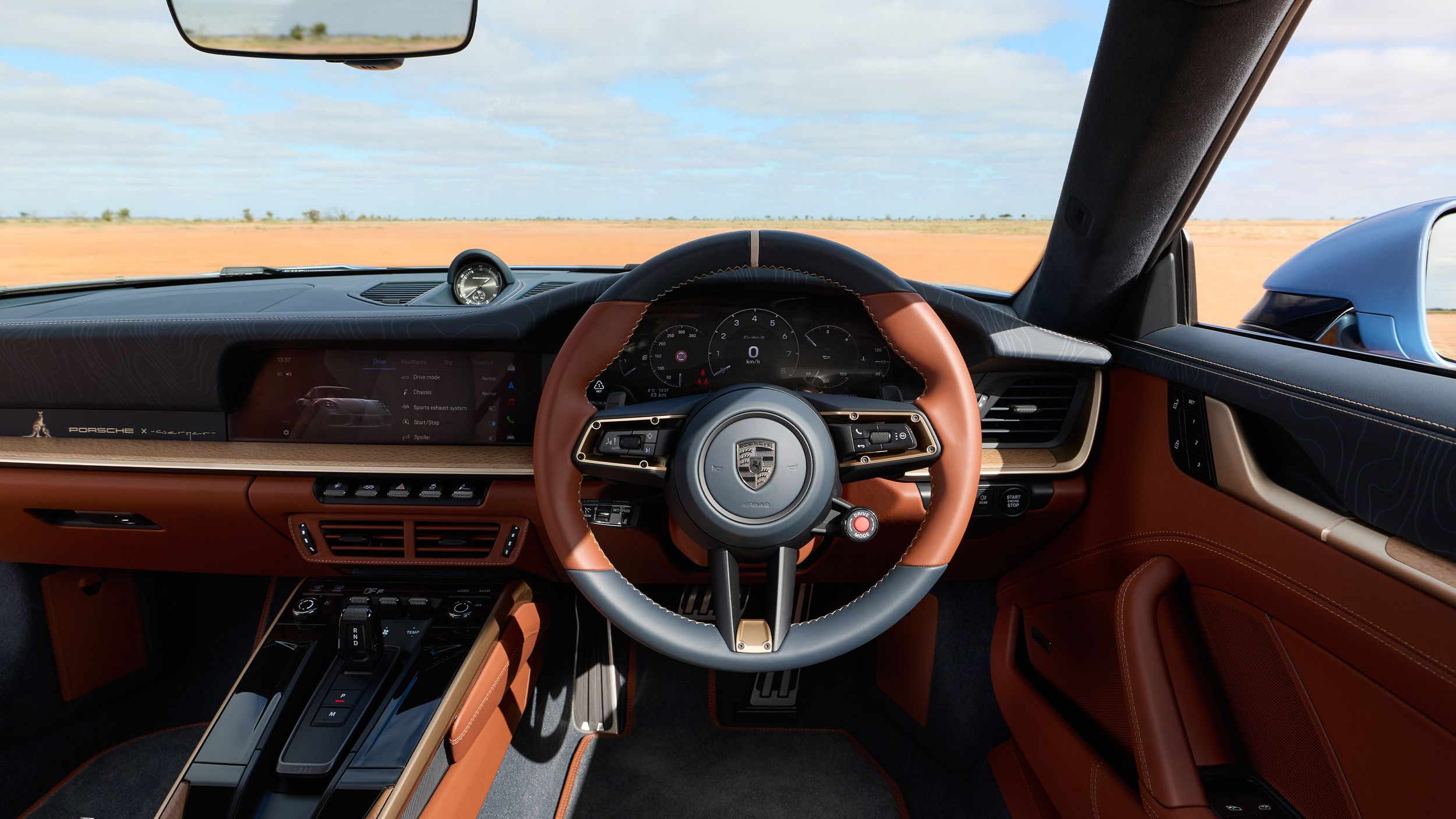 Interior shot of the 911 Turbo S Land Down Under showing the Coolibah Brown and Dark Night Blue leather cockpit with the steering wheel.