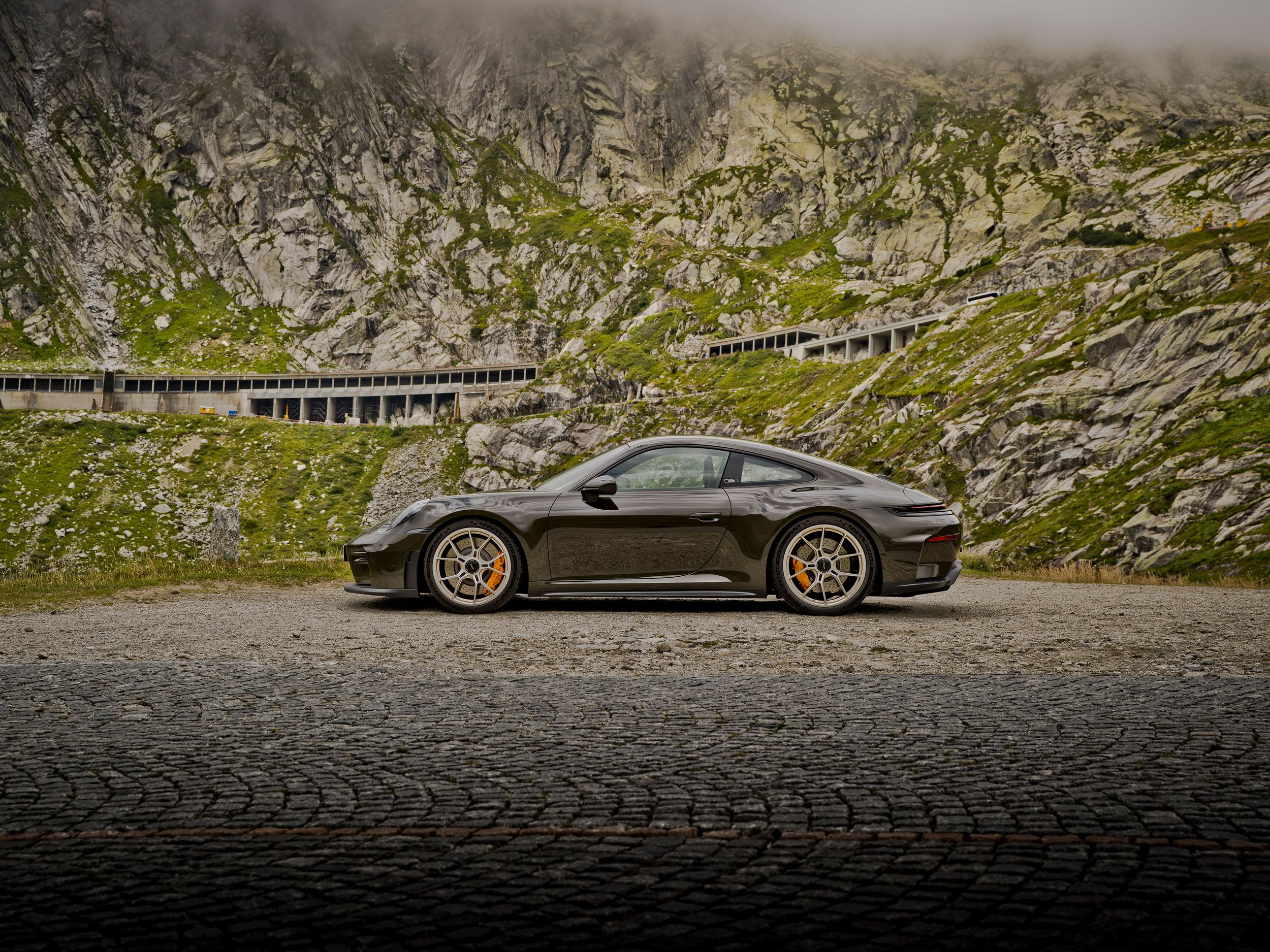 Porsche 911 GT3 Bergsport mit gelben Bremssätteln im Seitenprofil vor felsiger Alpenlandschaft.