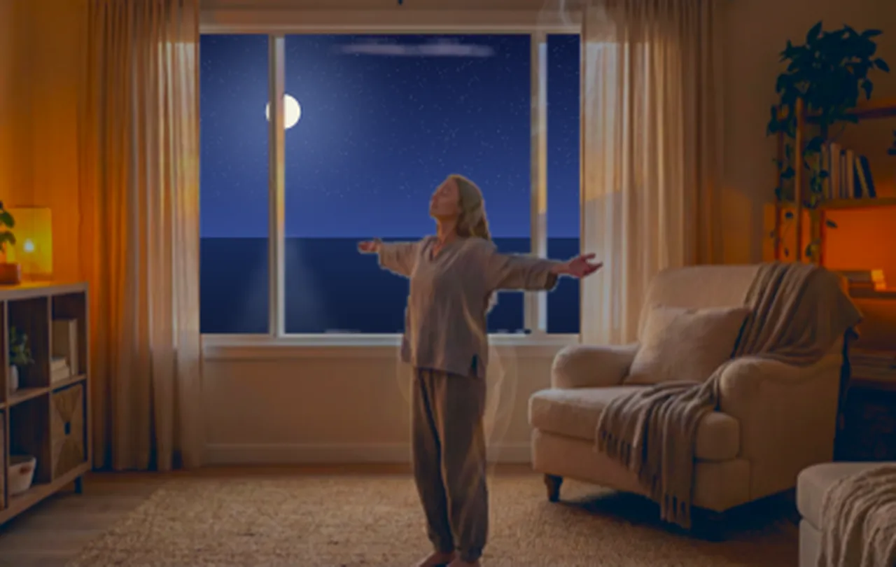 Eine Frau steht mit ausgebreiteten Armen am Fenster, draußen Nacht mit Mond über dem Meer