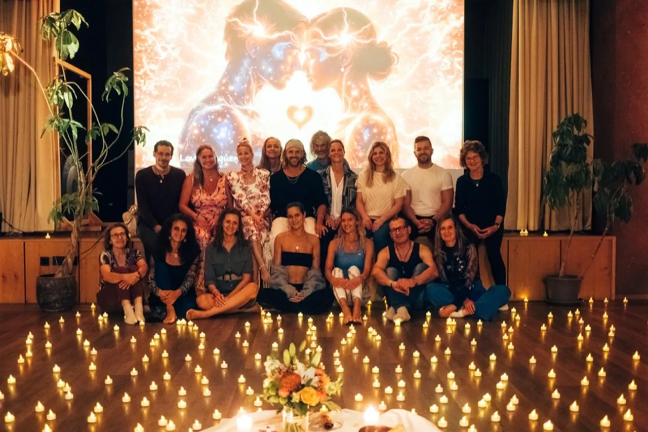 Tantra-Seminar-Gruppe posiert mit Kerzen am Boden vor farbiger Projektion bei Tantra-Workshop mit Anna und Yves