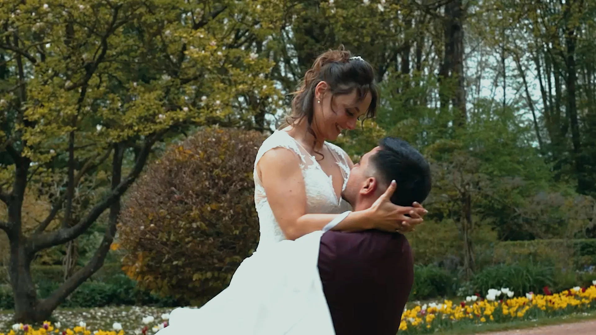 un marié tient sa femme dans ses bras, elle a les mains derrière sa tête et lui sourit