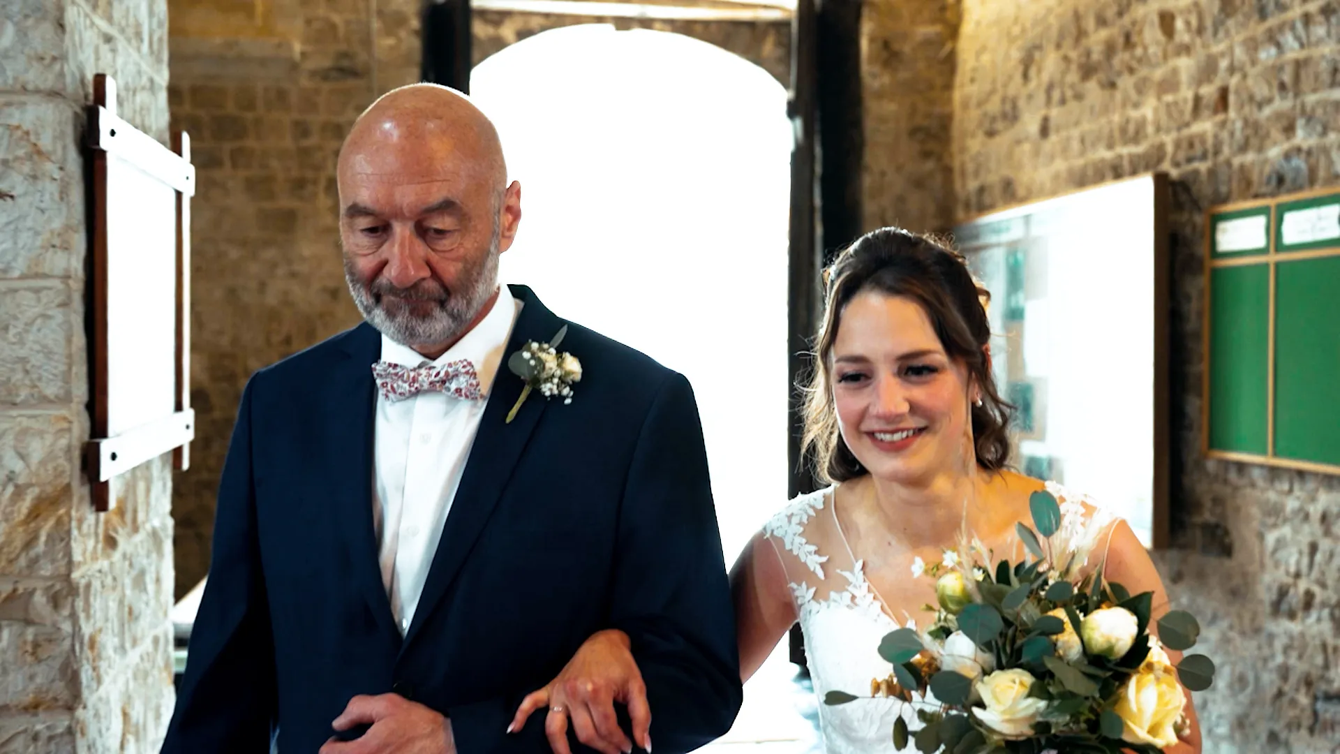 une jeune mariée et son père entrent dans l'église, elle lui tient le bras