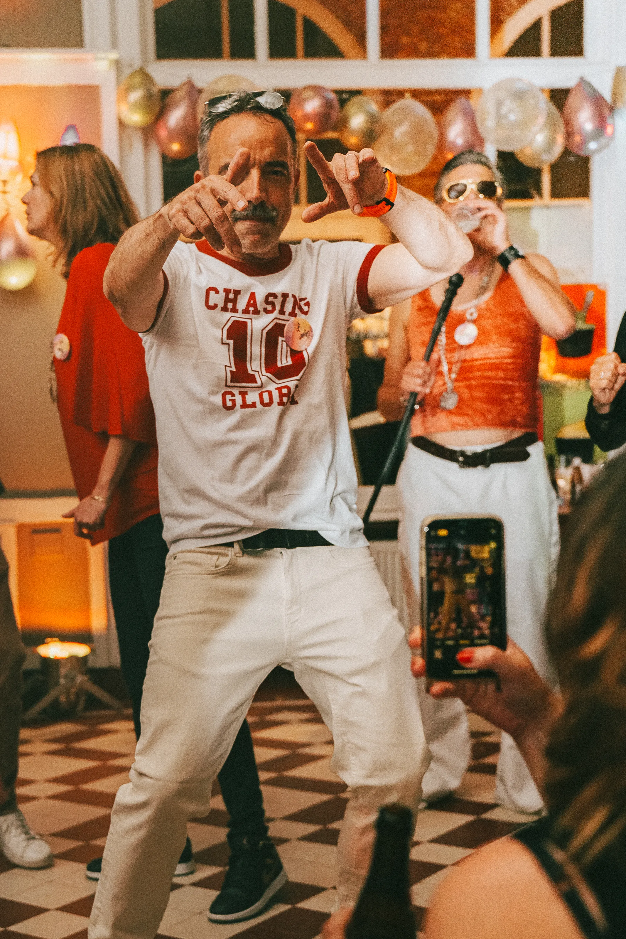 sur la piste de danse, une homme habillé en blanc danse avec les mains en l'air