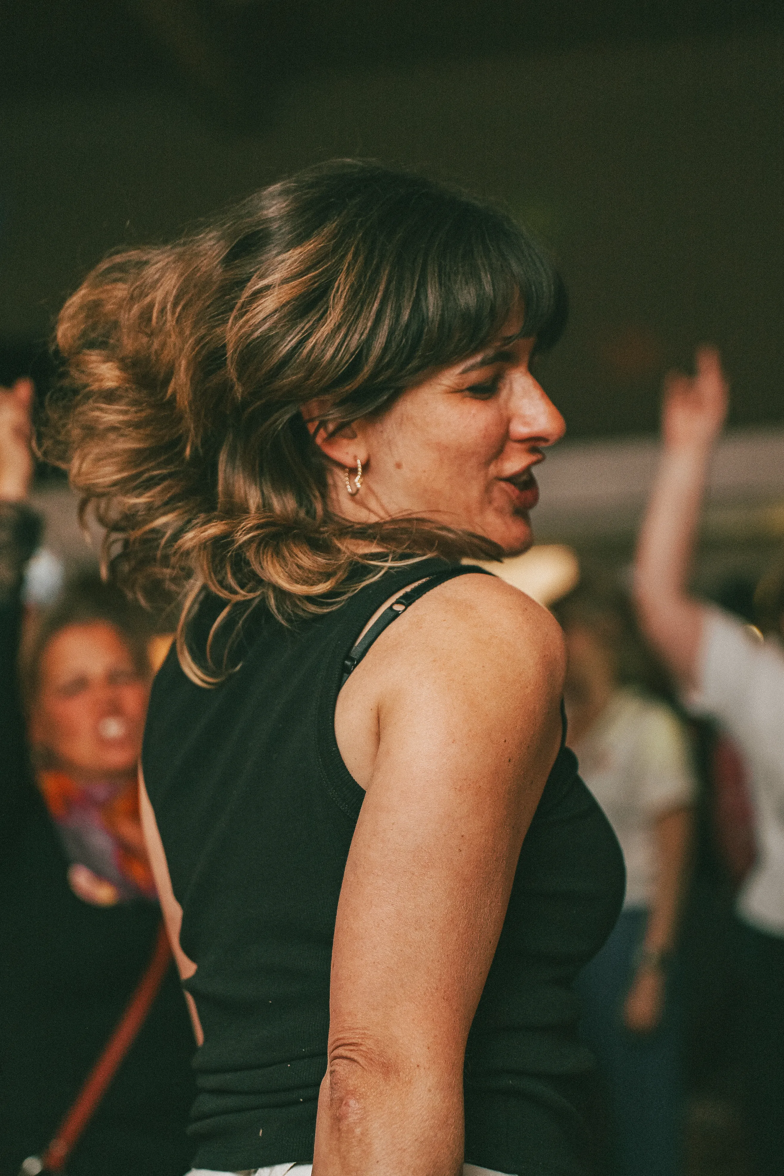 de dos, une jeune femme aux cheveux longs porte un débardeur noir et danse