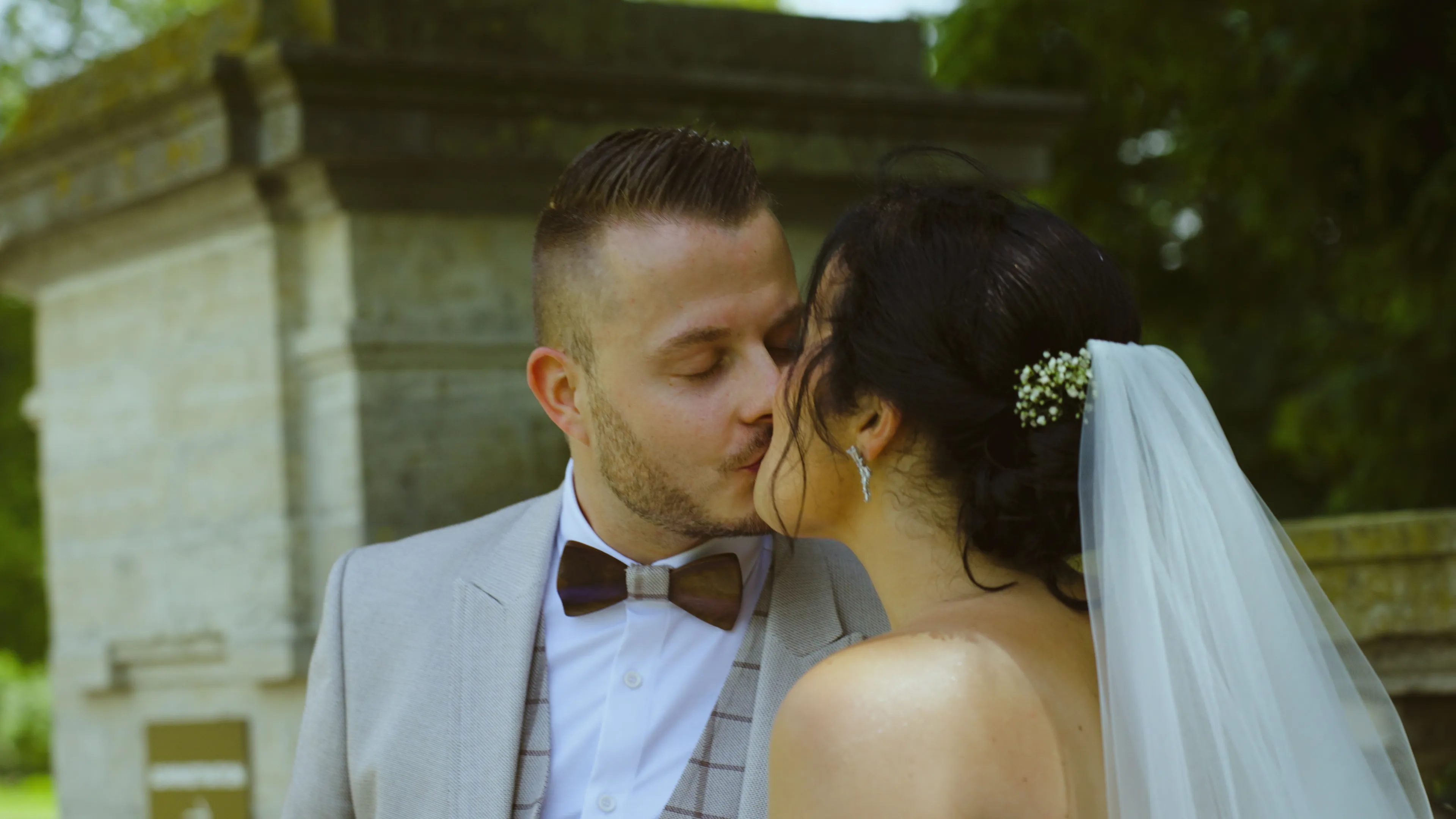 un couple de jeune mariés s'embrasse, la mariée est de dos