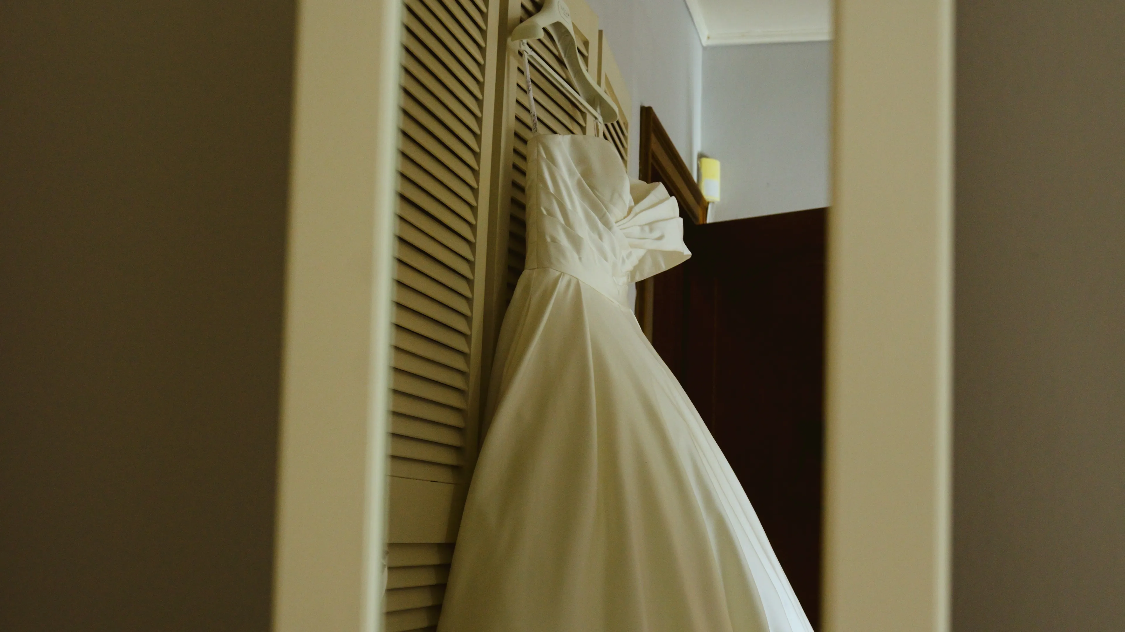 une robe de mariée blanche est accrochée devant une armoire